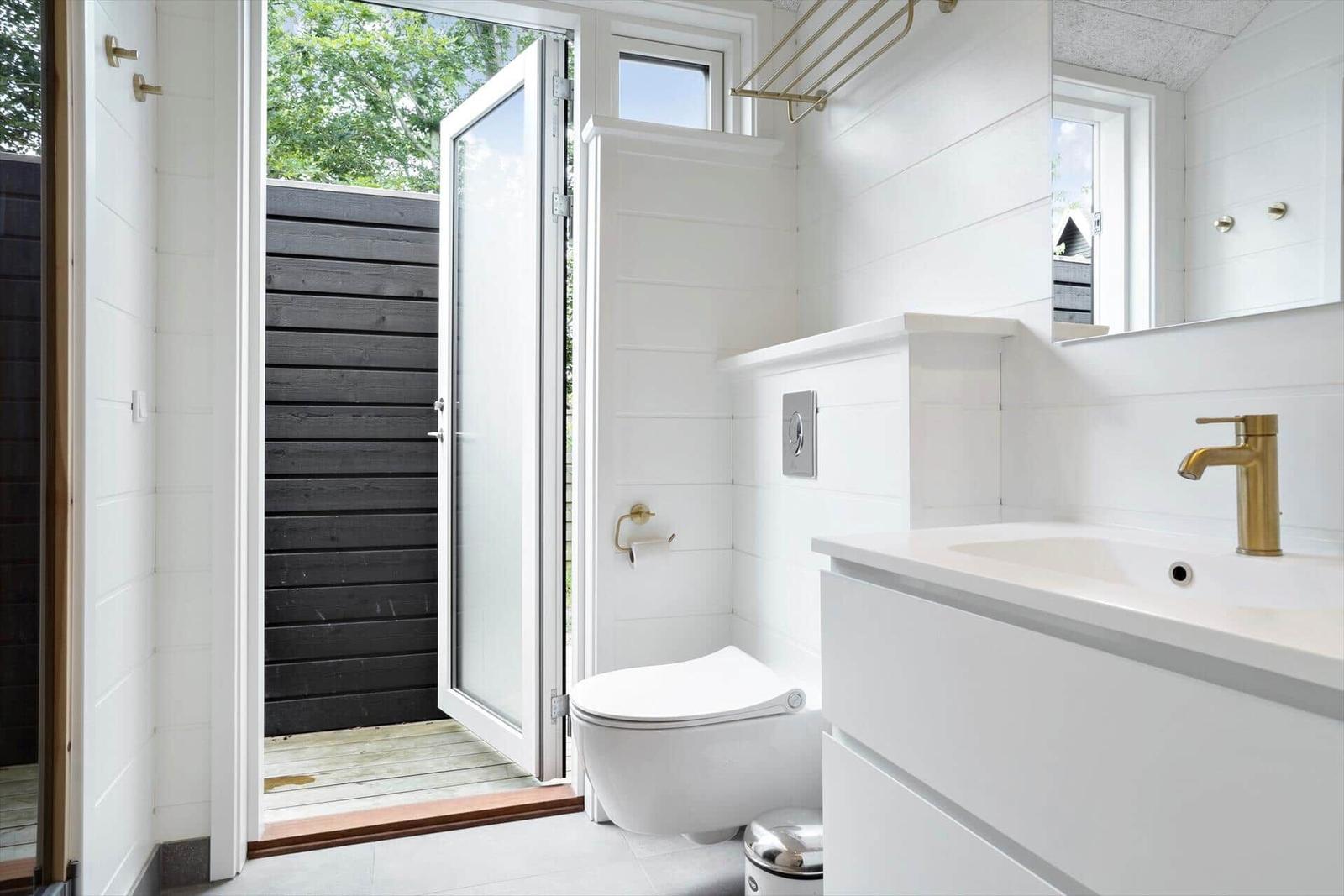 Badezimmer mit Toilette, Waschbecken und Dusche im Freien.