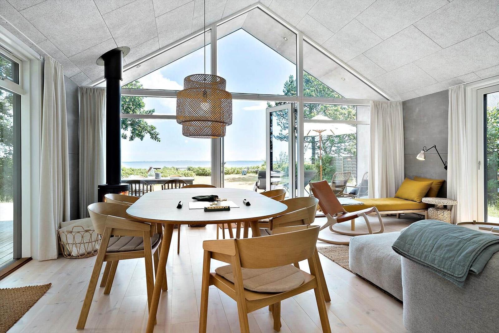 Ein Esszimmer mit Holztisch, Stühlen und Blick aufs Meer.