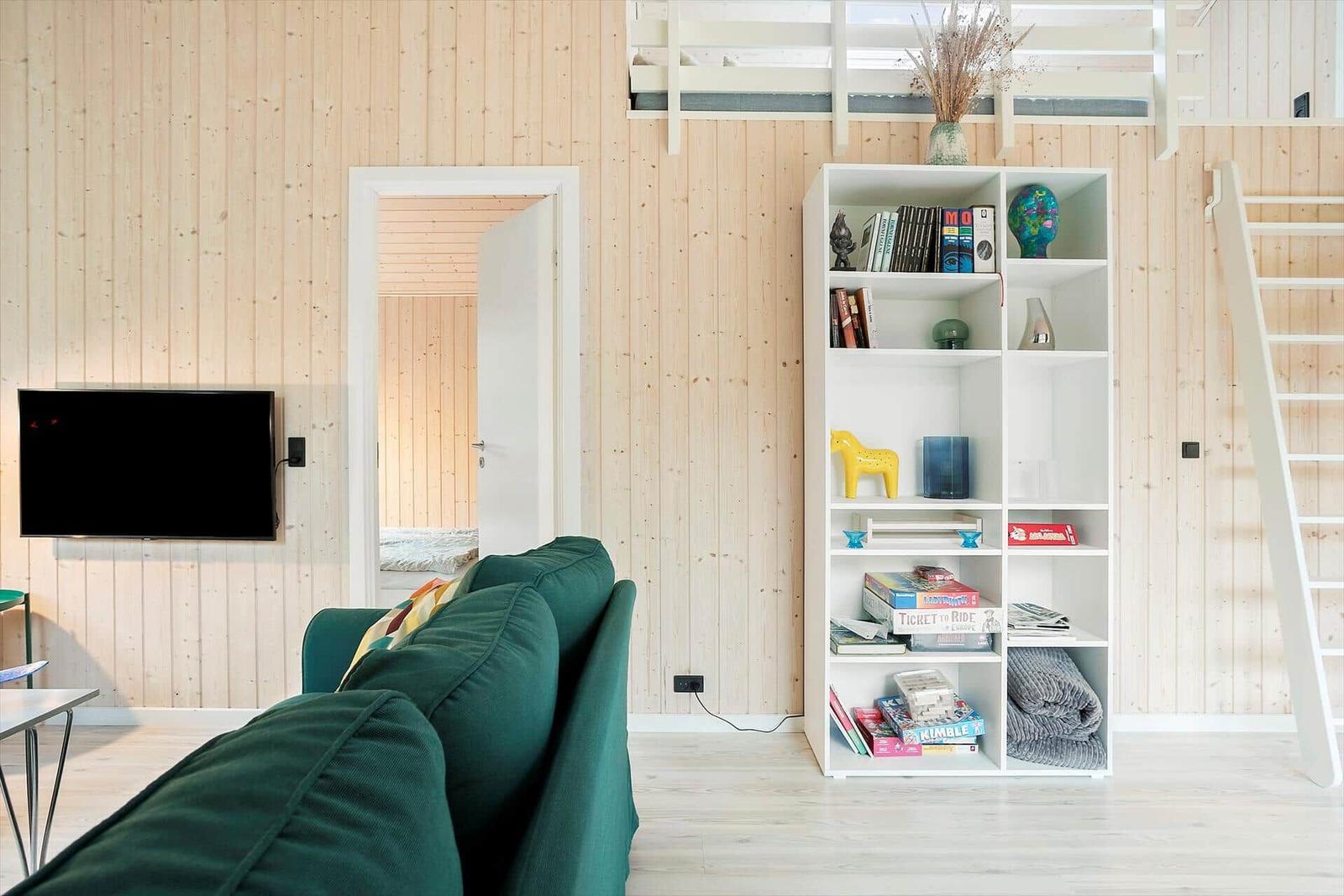 Living room with green sofa, bookshelf, and loft bed.