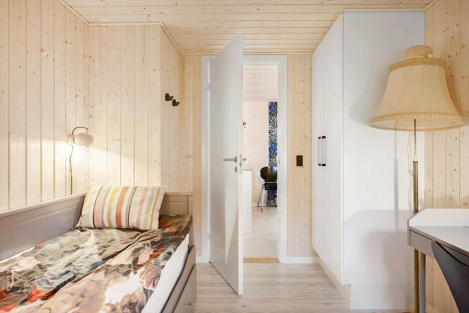 Bedroom with bed, wardrobe, and floor lamp. Passage to another room.