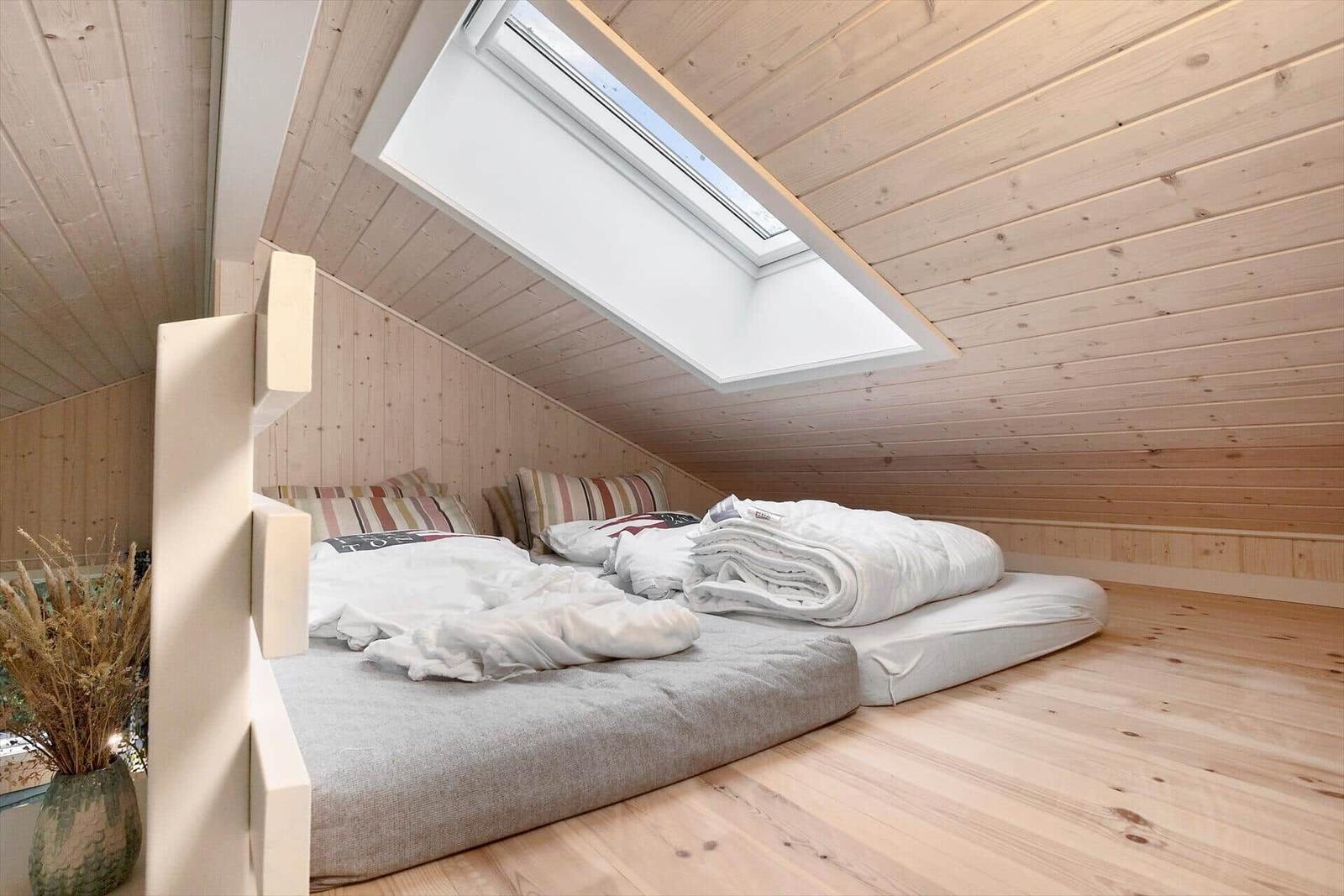 Bedroom with skylight, wooden walls, and floor mattress.