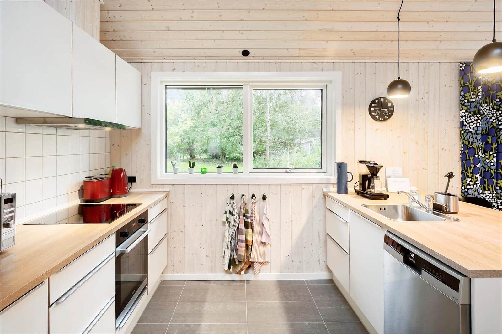 Kitchen with wooden walls, window, sink, and appliances.
