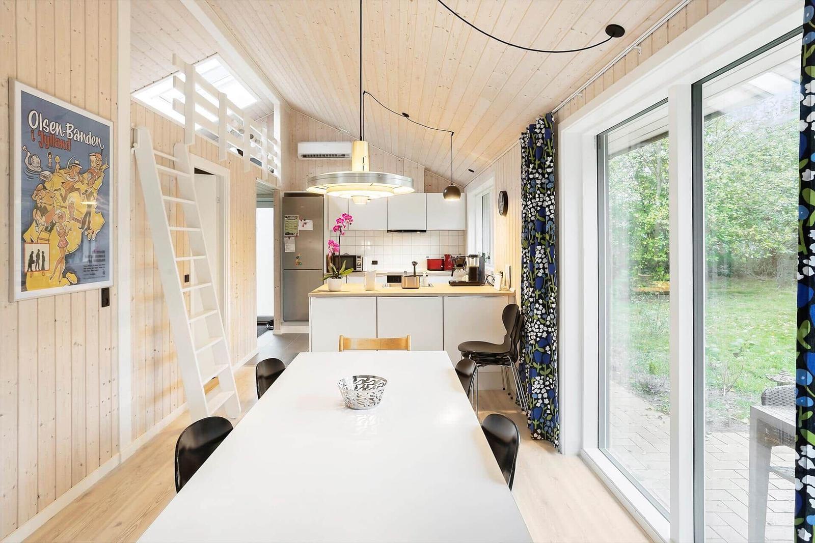 Kitchen with dining table, sleeping area, and large window to outdoor terrace.