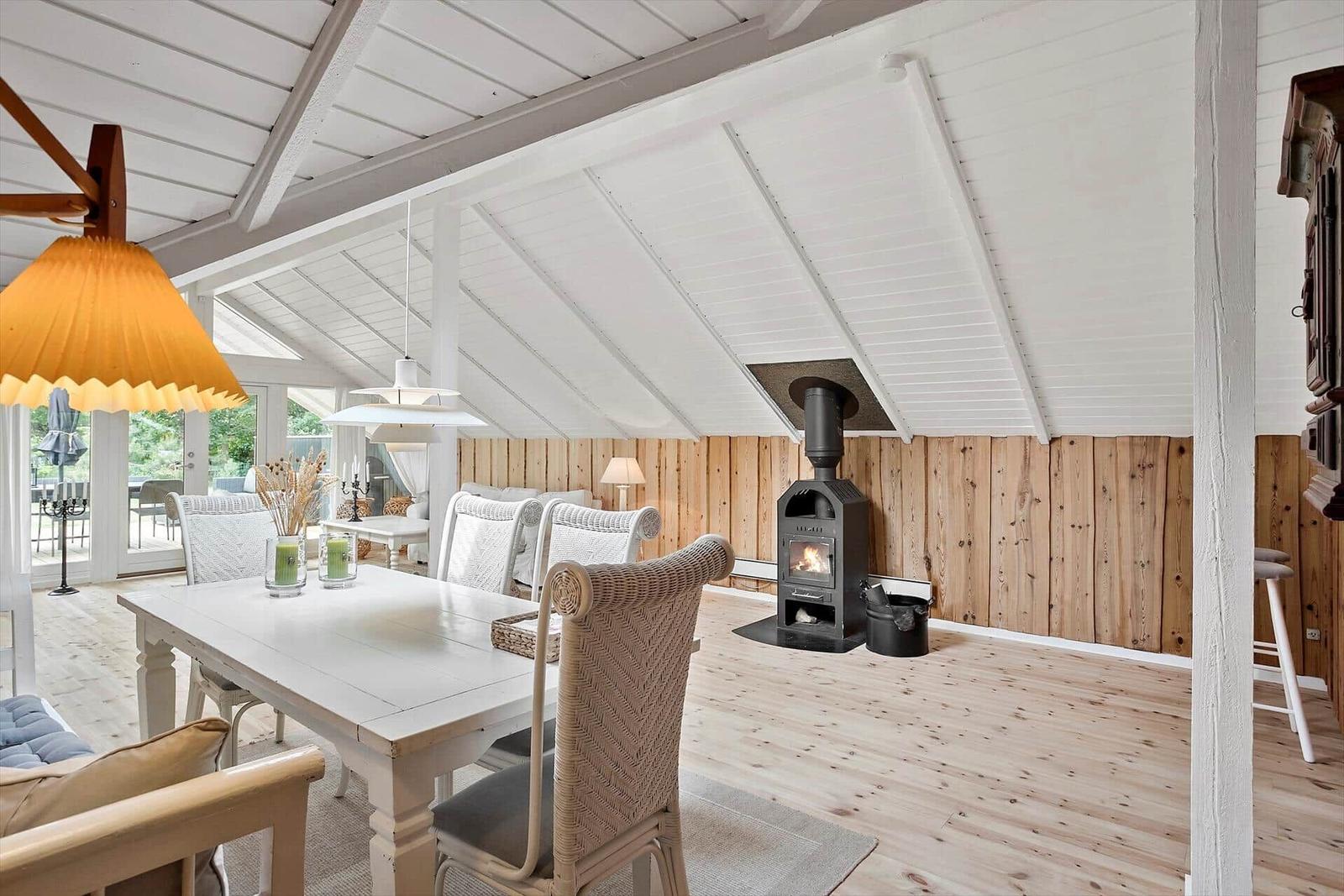 Haus mit Essbereich, Kamin und Holzwand. Holzfußboden und weißer Deckenrahmen.
