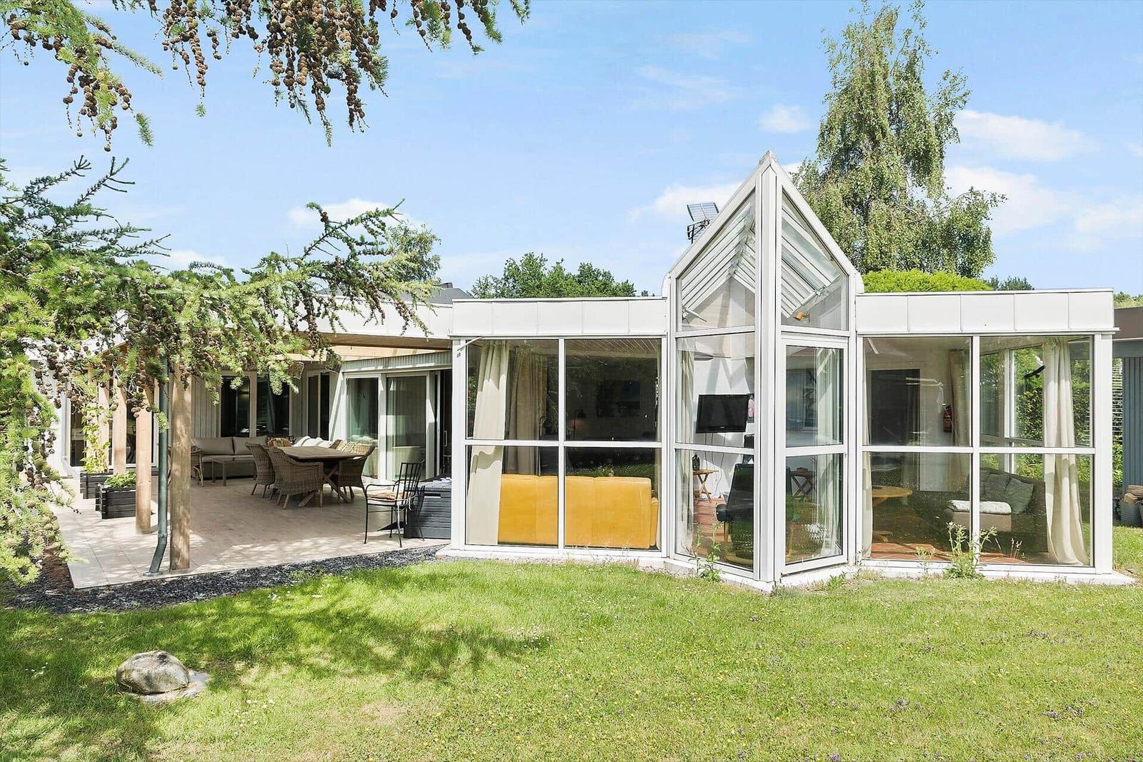 Modernes Haus mit großem Glasbereich und Terrasse im Grünen.