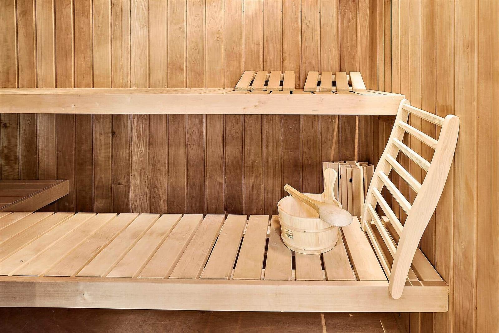 Sauna mit Holzbank, Eimer und Besen. Holzwände und -bänke.