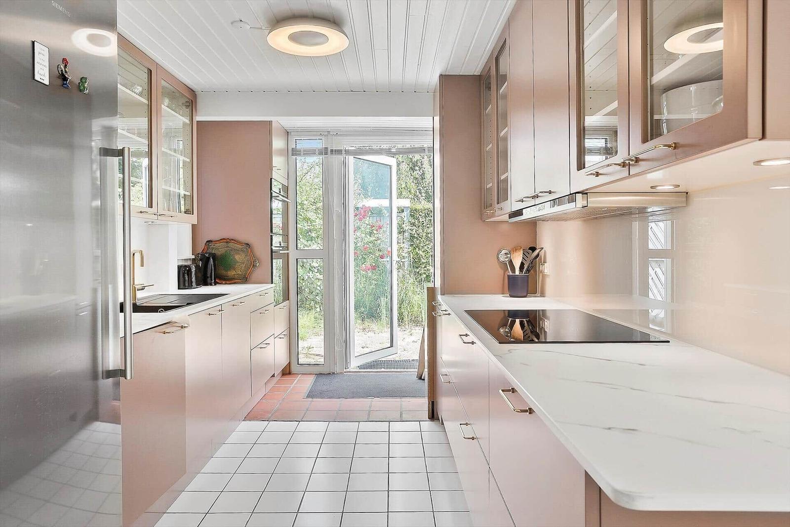 Moderne Küche mit Edelstahlkühlschrank und Marmorarbeitsplatte. Durchgang zur Terrasse.