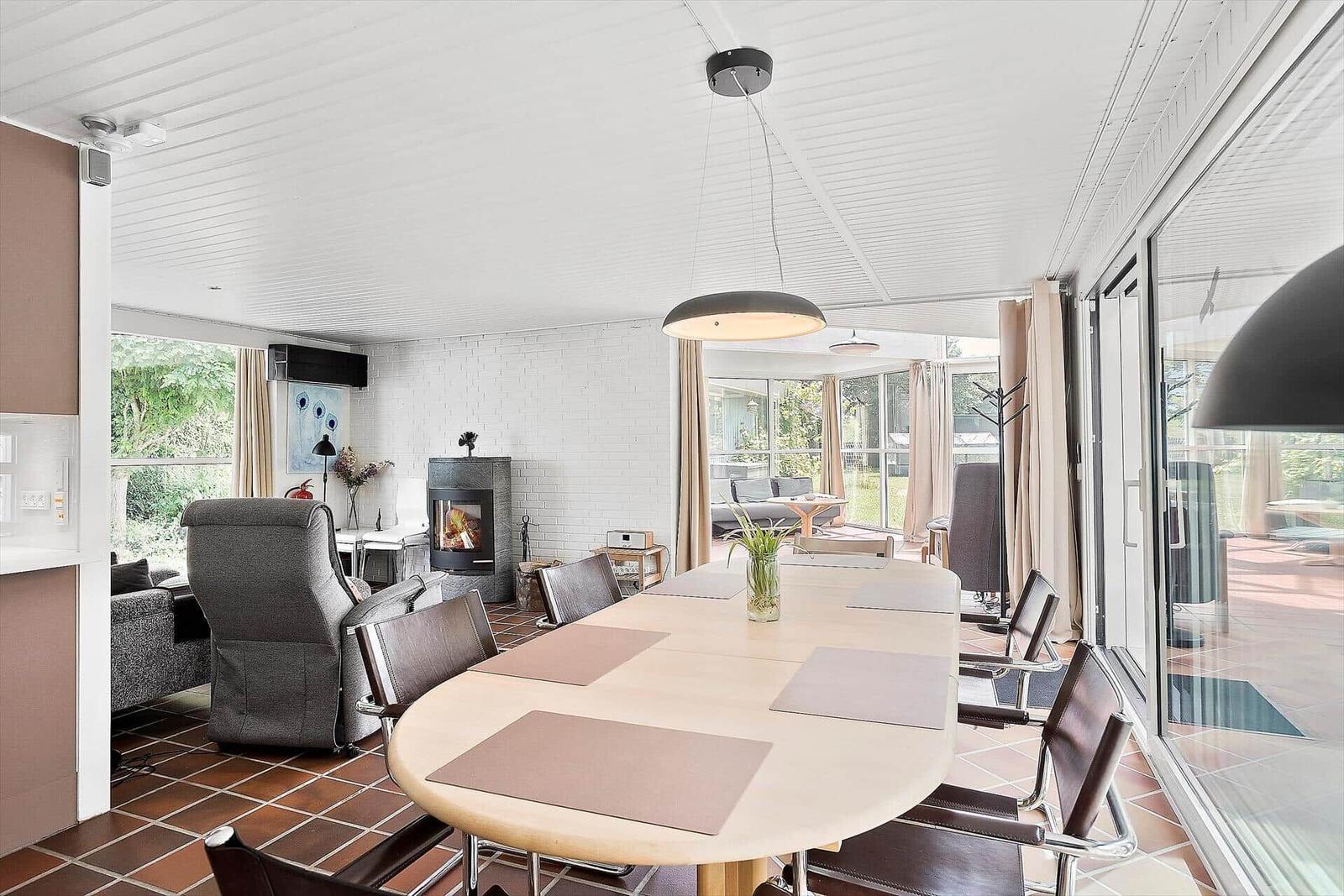 Esszimmer mit Tisch und Stühlen, Kamin und Glasfront zur Terrasse.