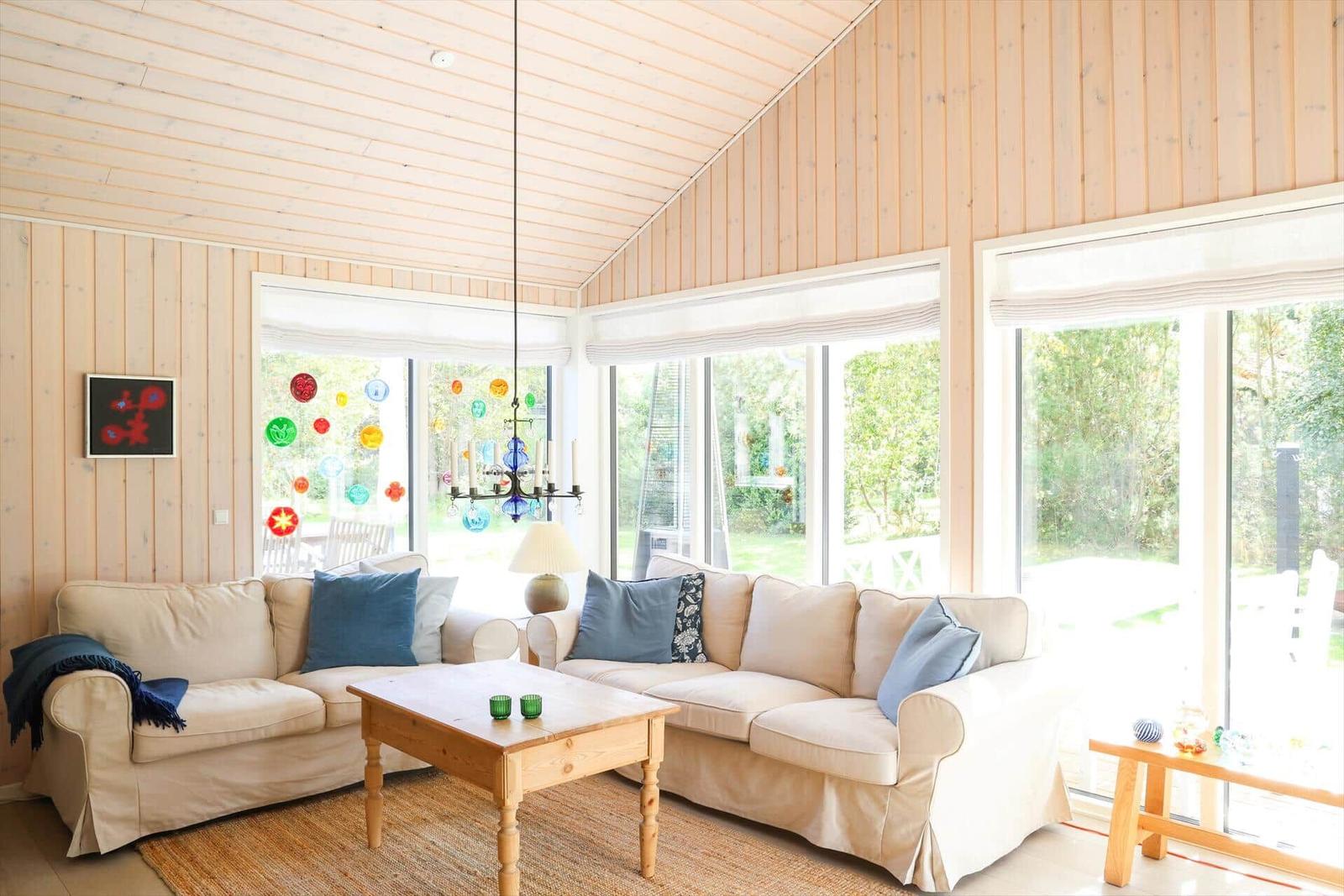 Wohnzimmer mit zwei Sofas, Holztisch und großen Fenstern zur Außensicht.