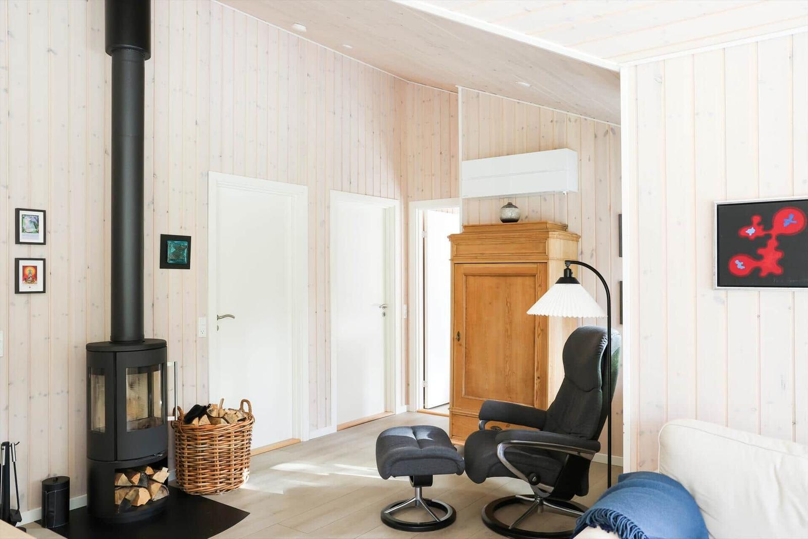 Wohnzimmer mit Holzwand, Kamin, Sessel und Schrank.