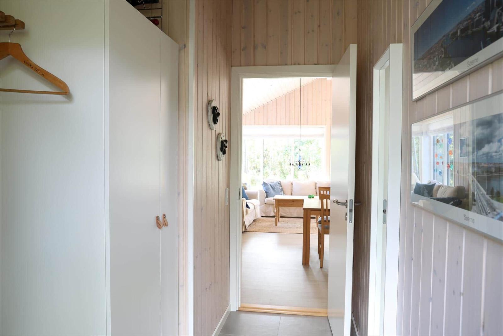 Flur mit Kleiderschrank und Blick in Wohn- und Essbereich mit Holzmöbeln.