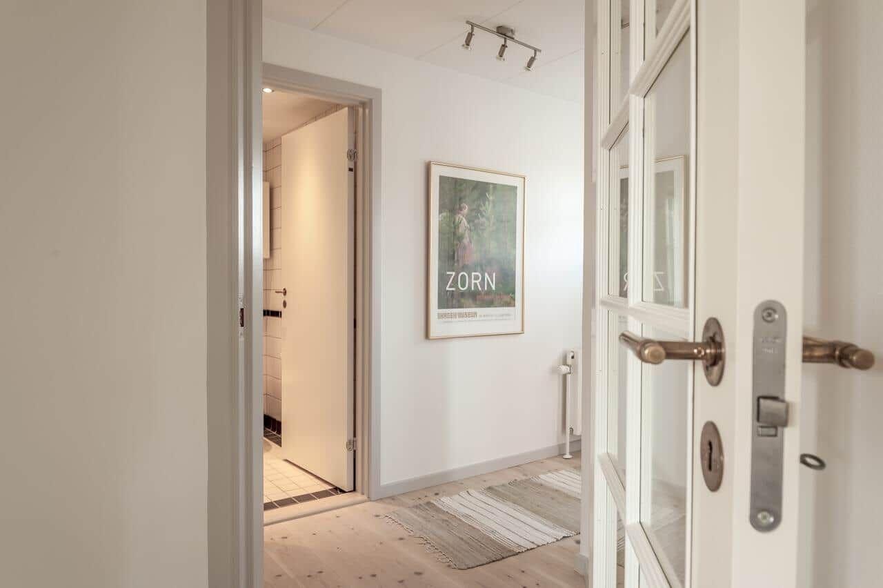 Hausflur mit Holzboden, Bild an der Wand und Tür zum Bad.