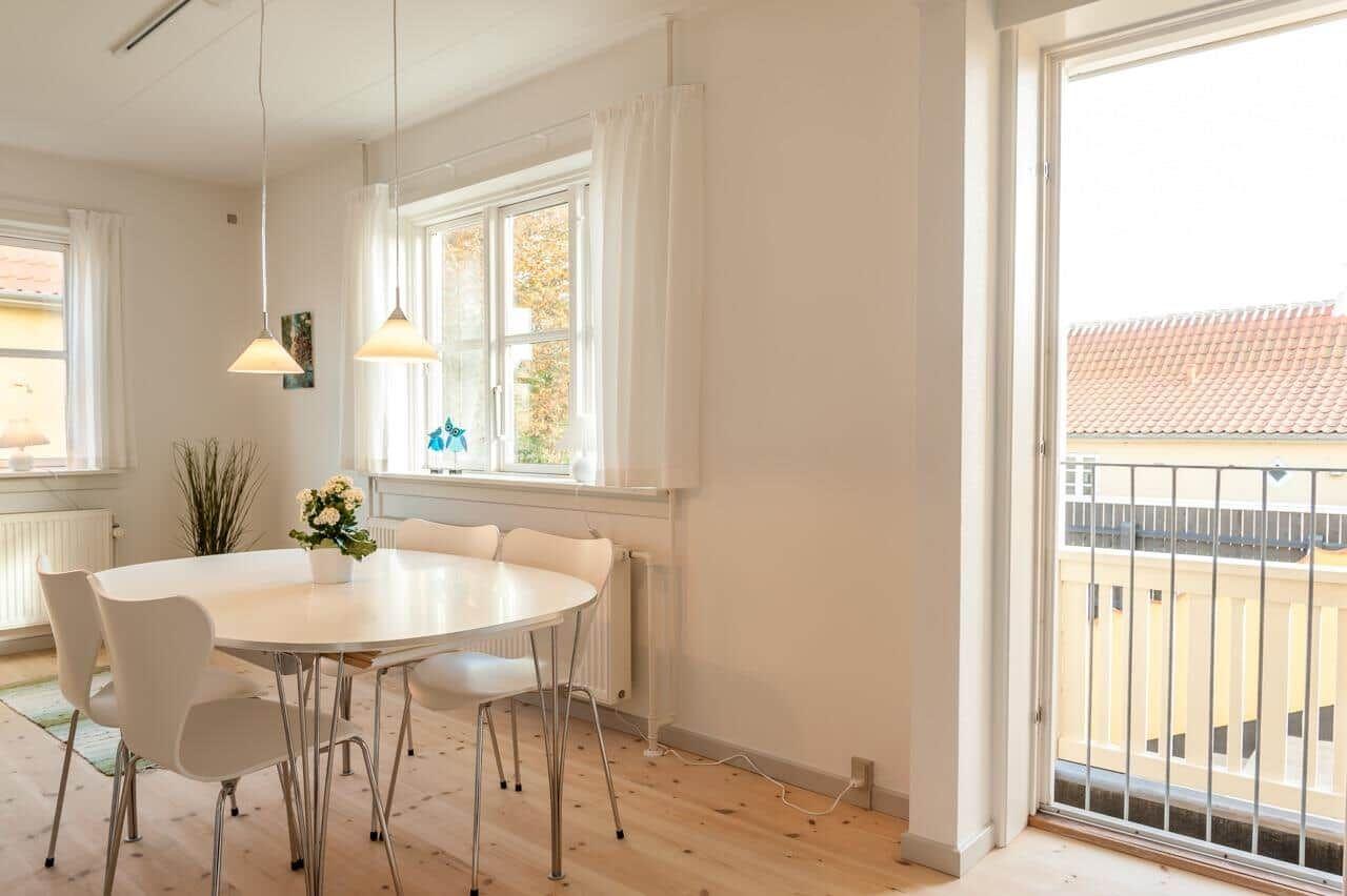 Esszimmer mit runden Tisch, weißen Stühlen und Balkontür.