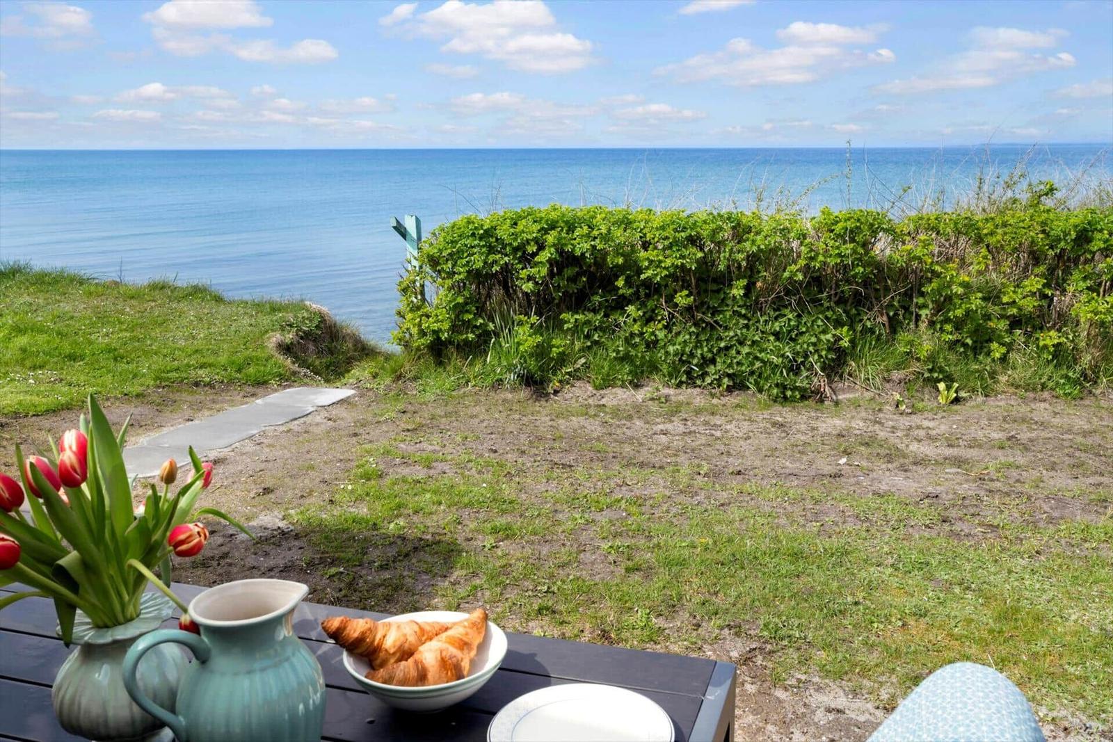 Tisch mit Croissants und Tulpen vor Meerblick