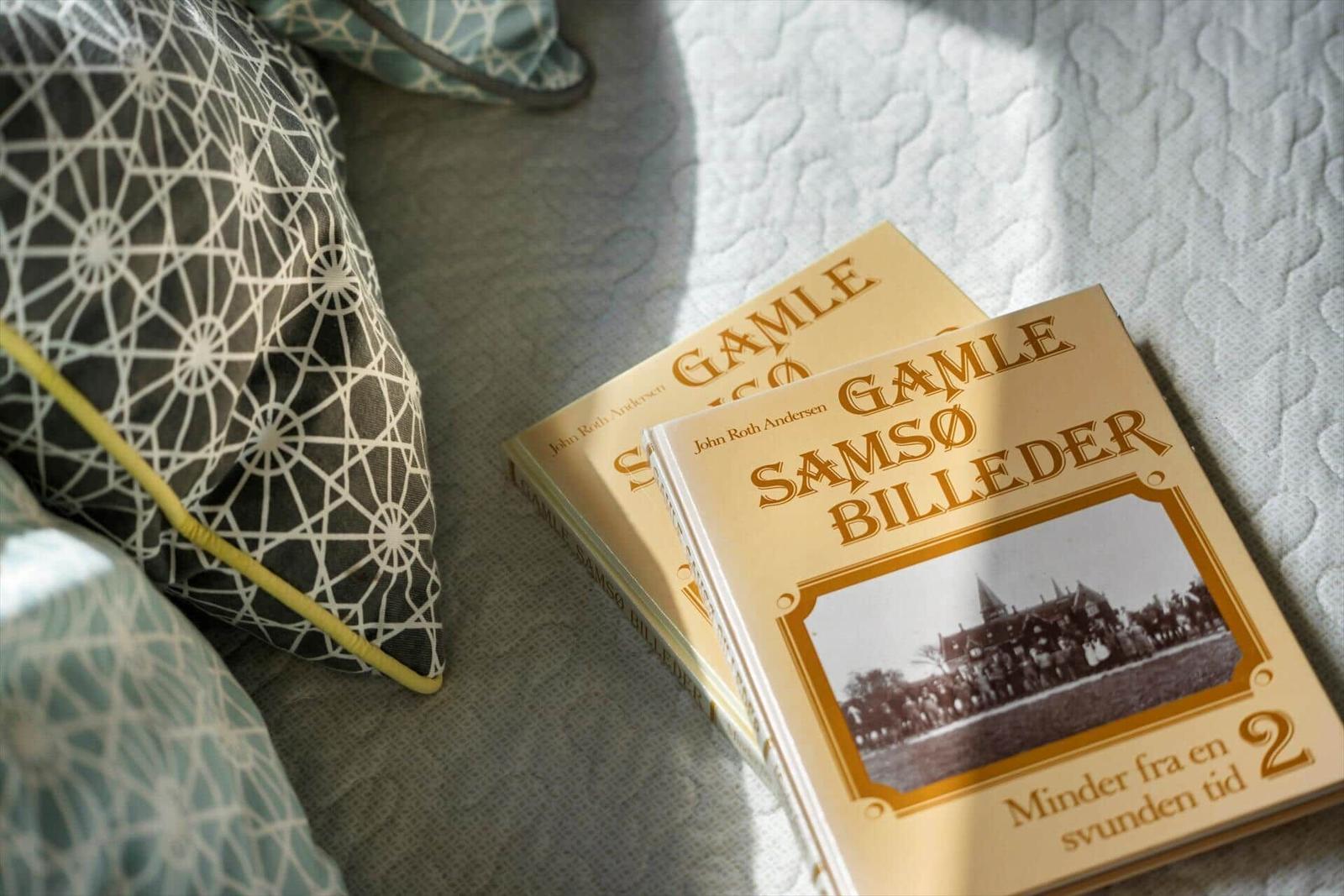 Zwei Bücher liegen auf einem Bett mit Kissen.