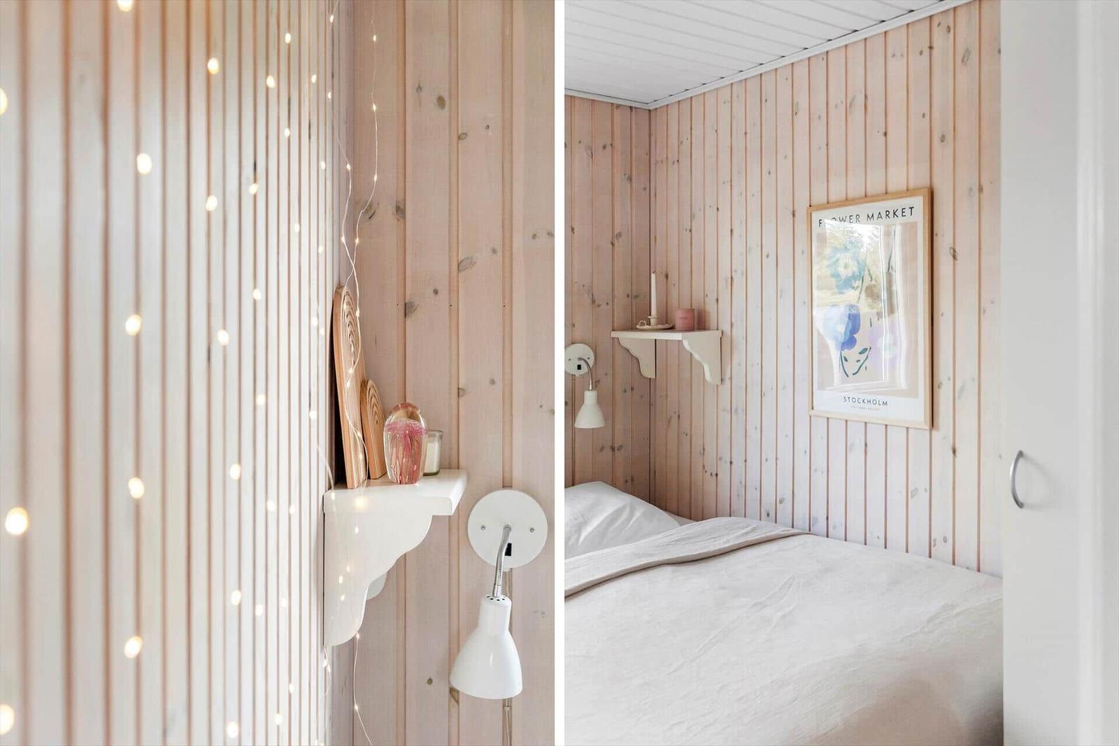 Bedroom with wooden walls, bed, wall shelf, and string lights.