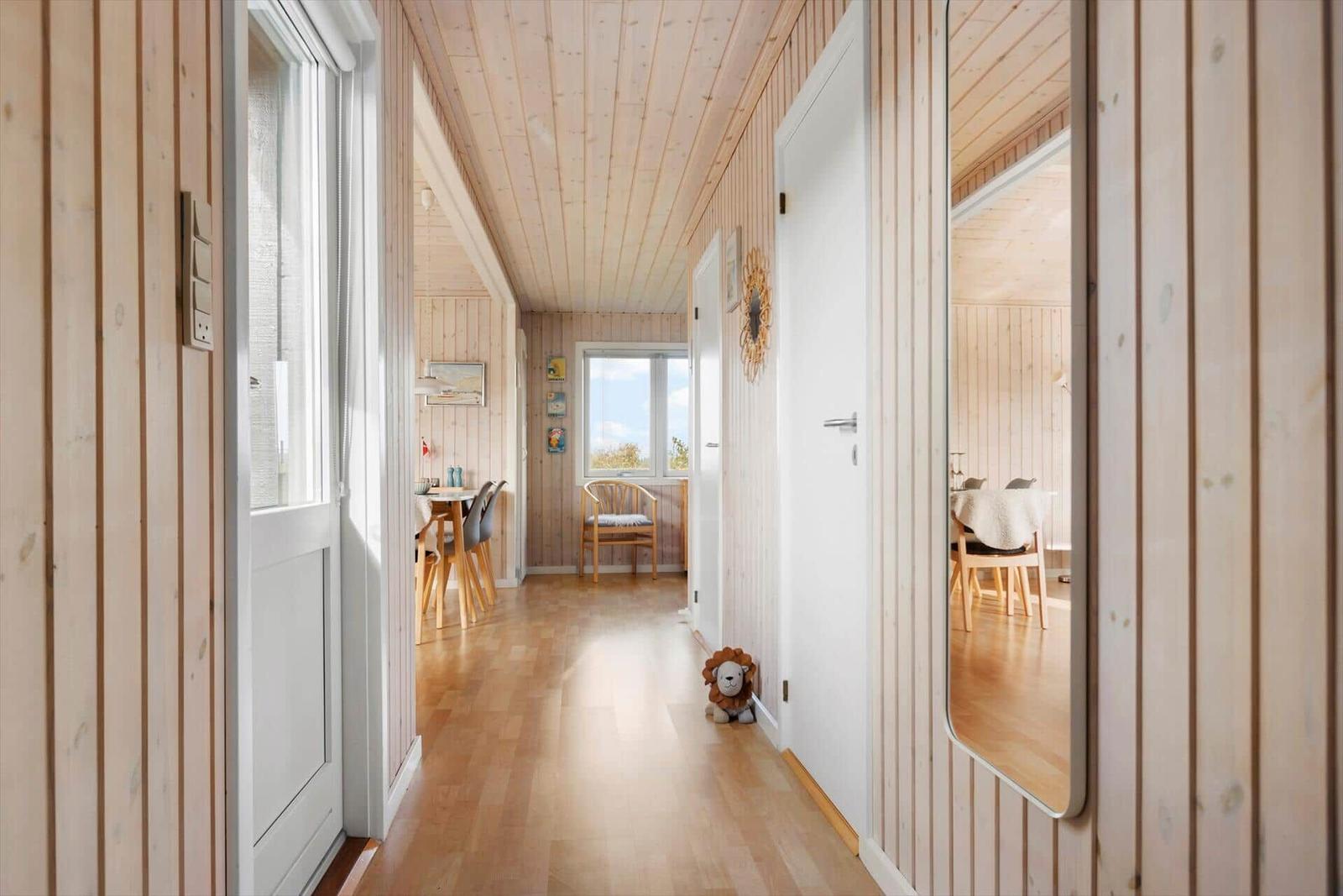 Hallway with wooden walls and door to dining room. Mirror and toy are visible.