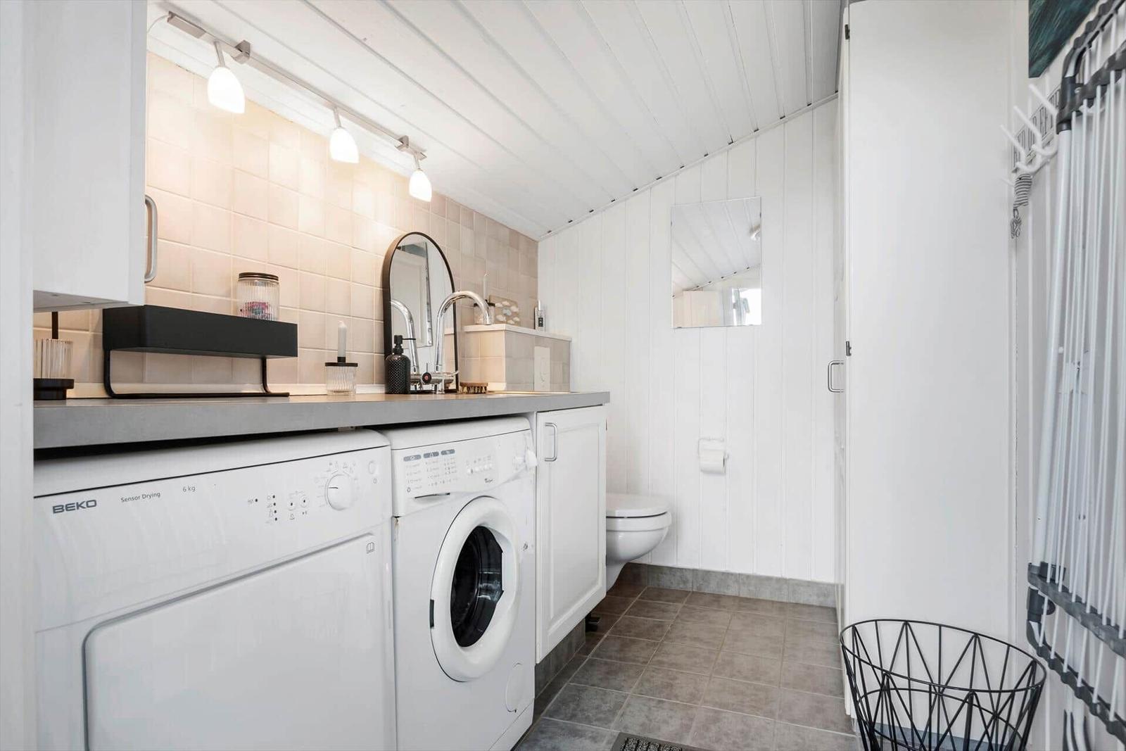 Washing machine and dryer in a bright laundry room with sink and toilet.