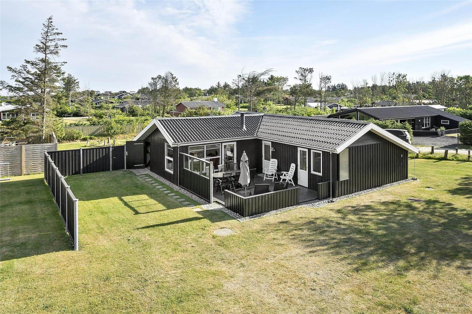 Modern villa with terrace, garden, and view of woods and neighboring houses.