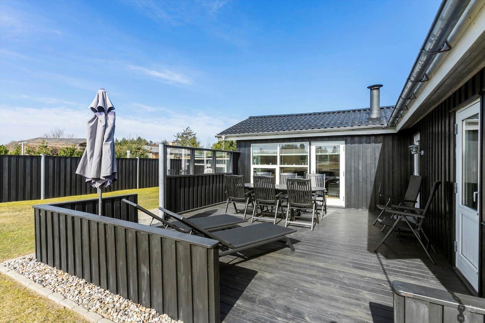 Deck with lounge chairs, table and chairs. Backyard with grass and fence.