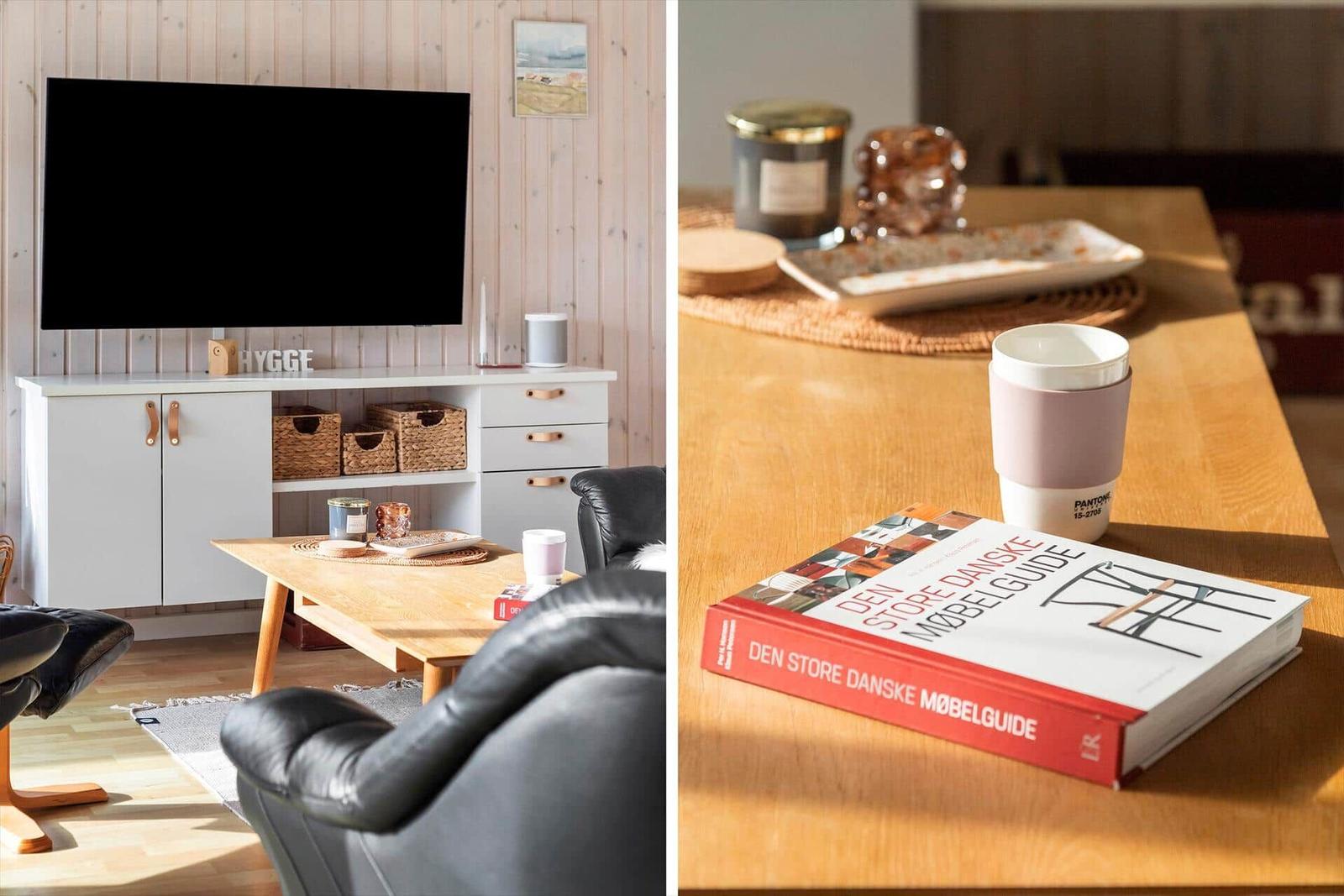 Living room with TV and black chairs. Table with book and cup.