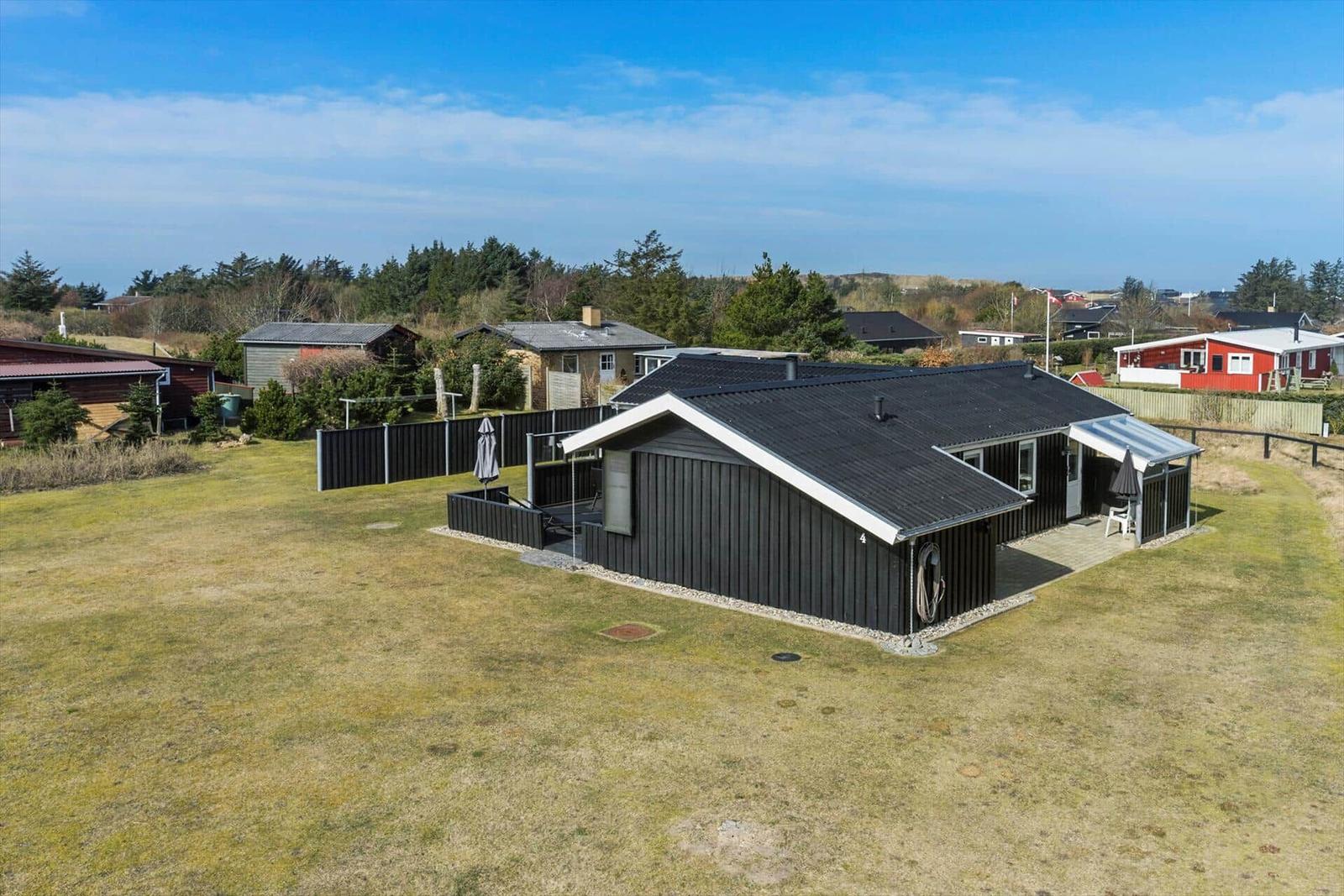 A black house with roof and terrace on a green plot.
