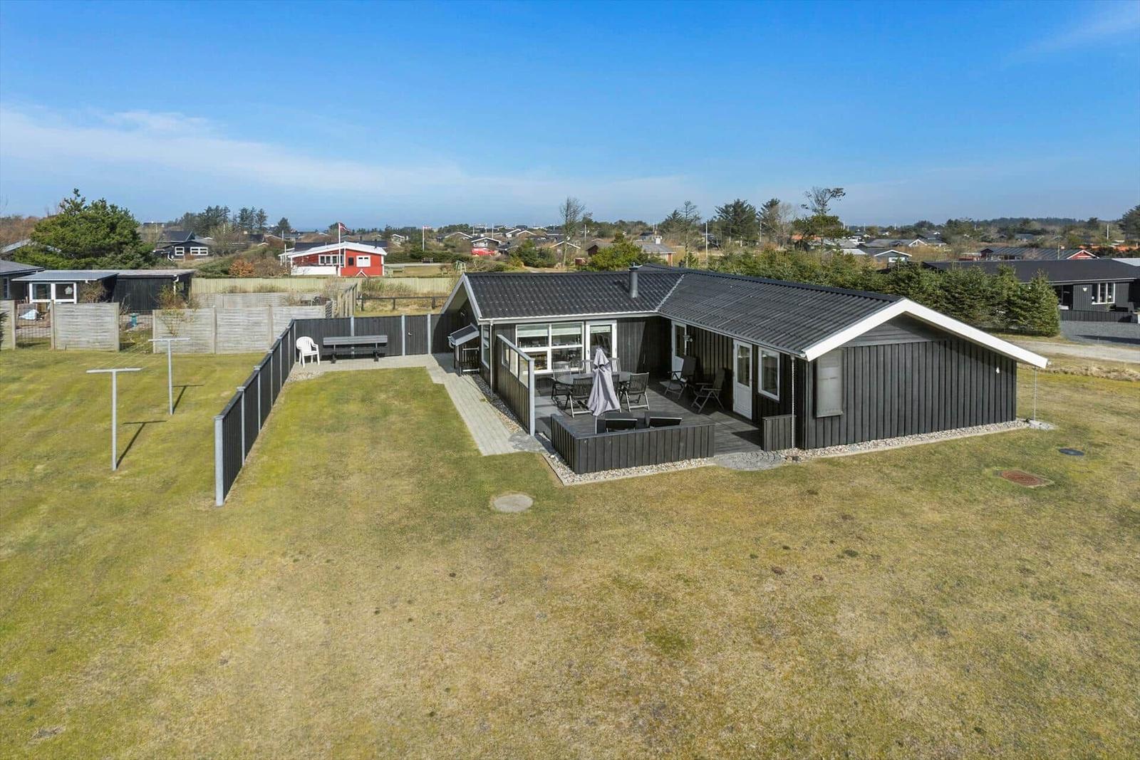 A modern house with terrace and garden. A large window front and a barbecue area are visible.