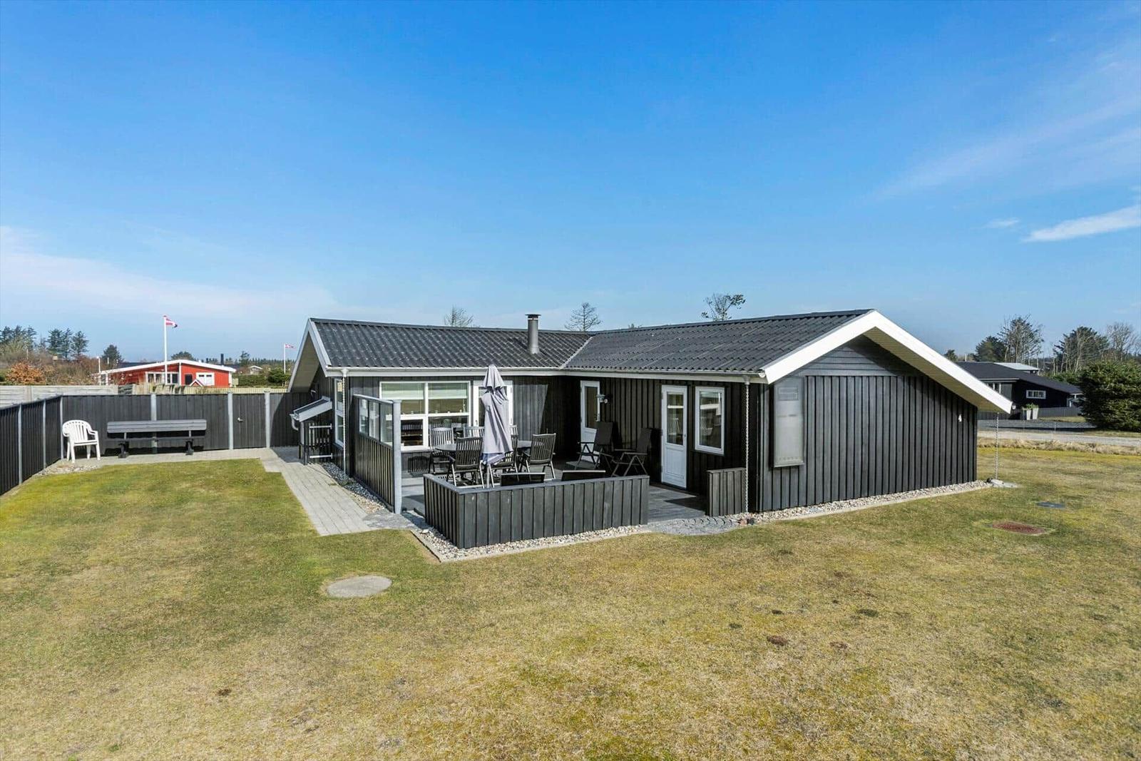 A modern holiday home with terrace, garden, and barbecue area. Backyard with seating.