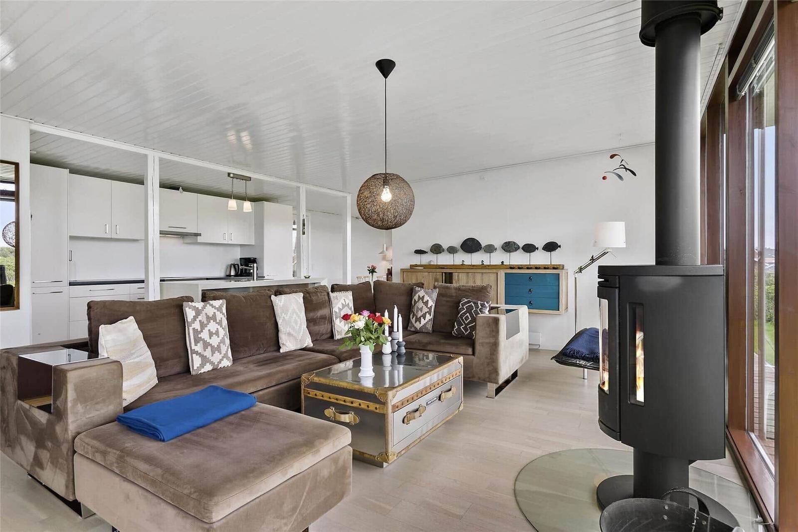 Wohnzimmer mit Sofa, Kamin und Küchenbereich im Hintergrund.