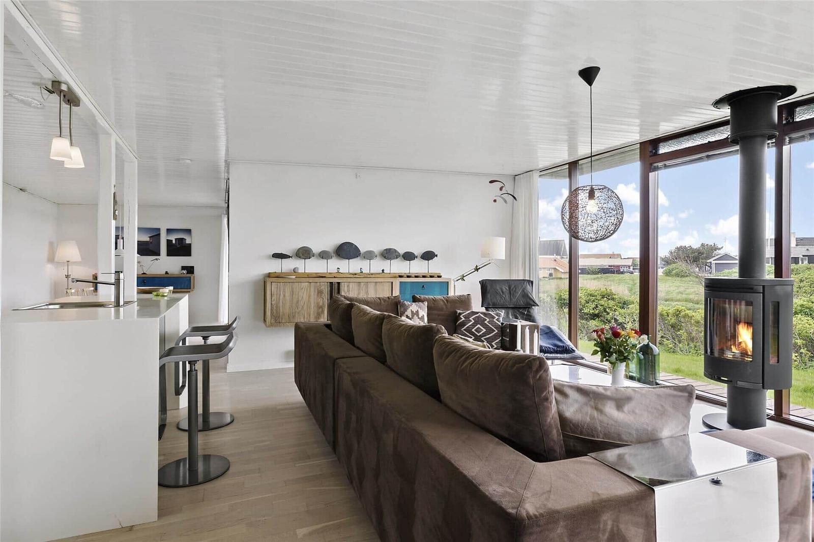 Wohnbereich mit Sofa, Kamin und großem Fenster zur Aussicht.