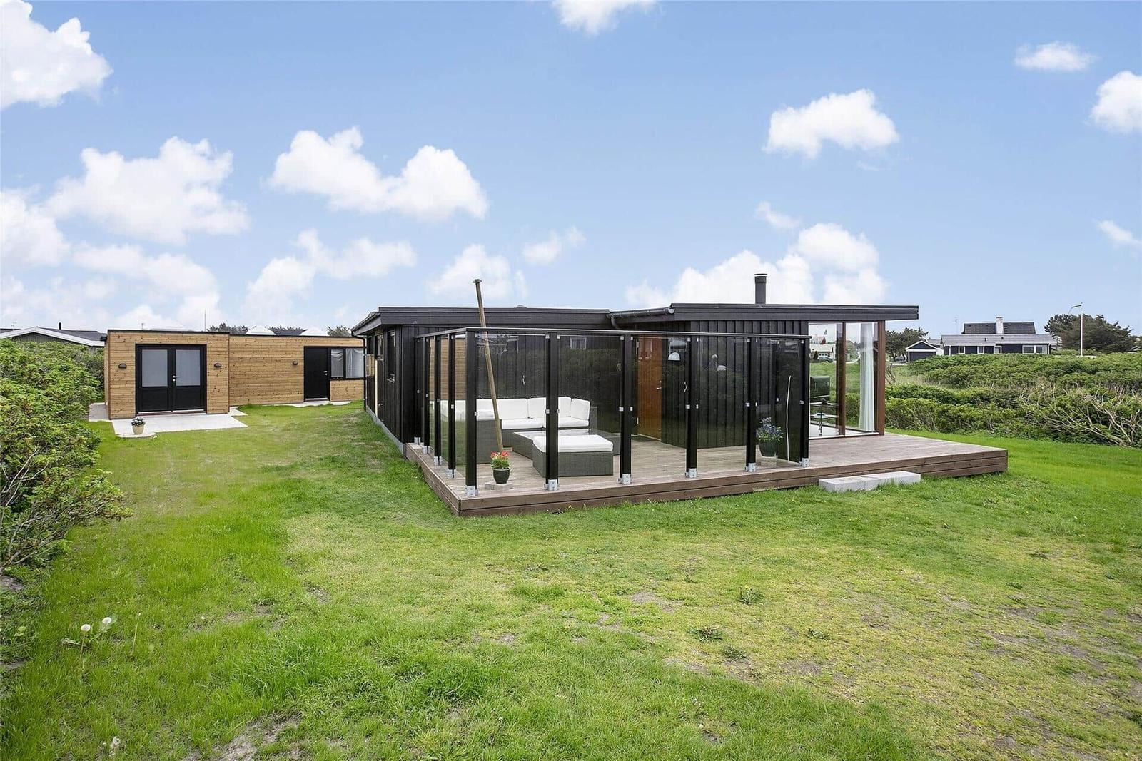Moderne Ferienwohnung mit Terrasse und Garten. Glaswand umgibt die Außenterrasse.