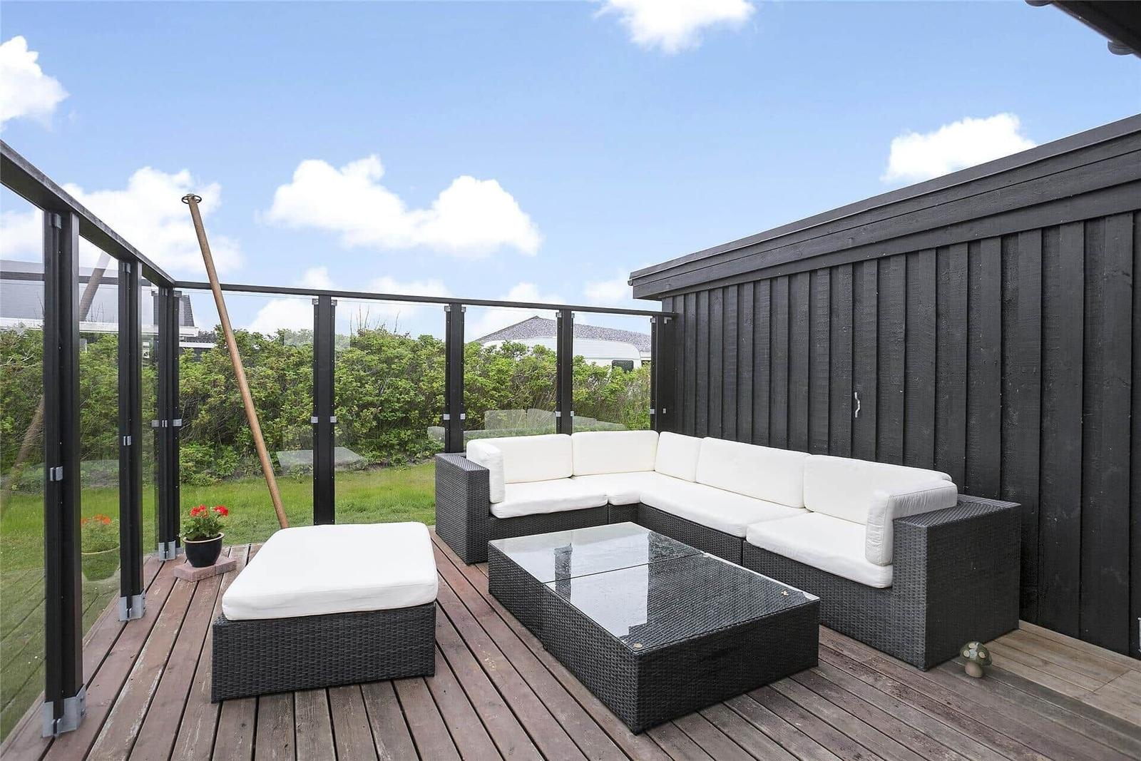 Terrasse mit weißer Außensitzgruppe und Glasgeländer