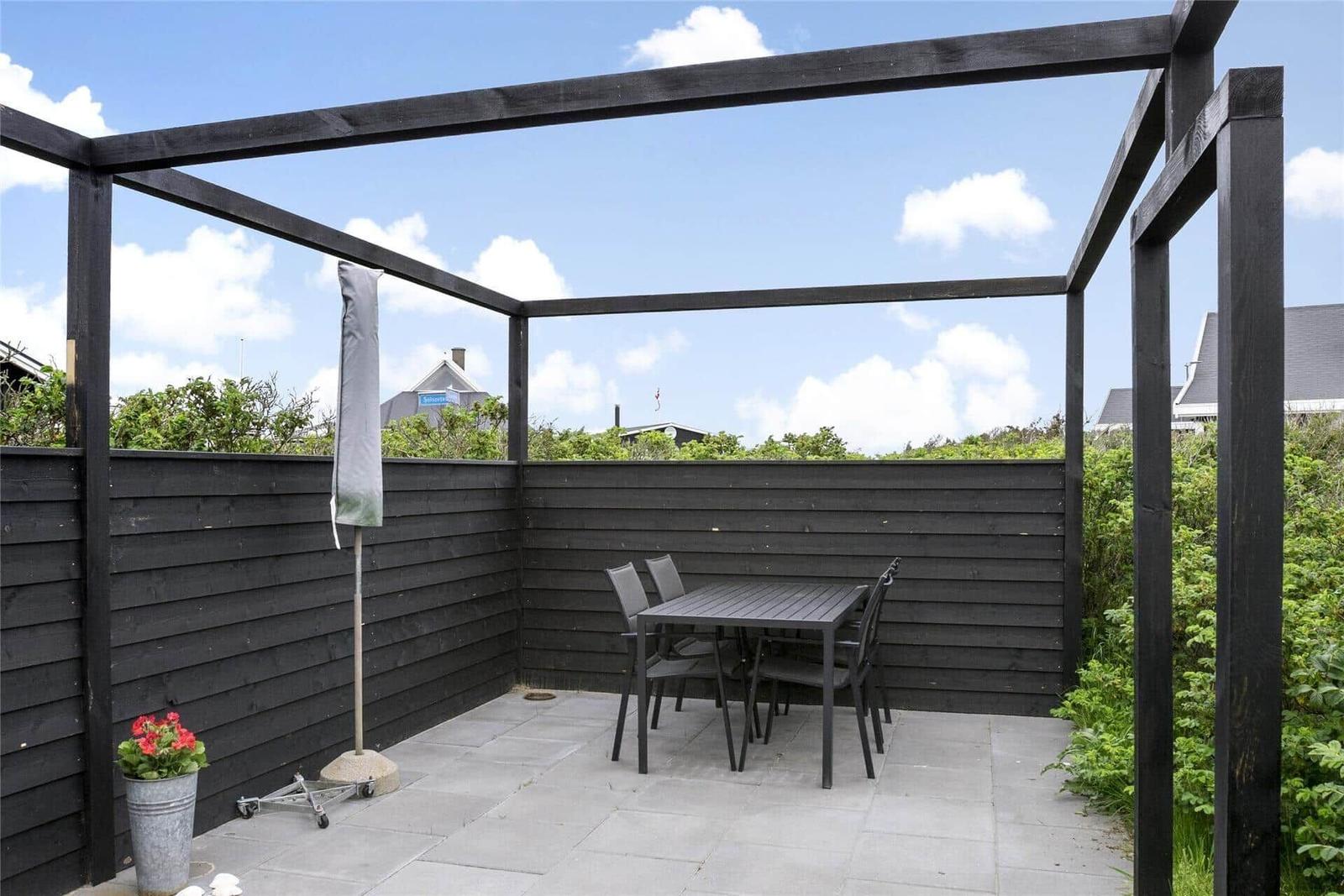 Terrasse mit Tisch, Stühlen und Sonnenschutz unter einem Pavillon.
