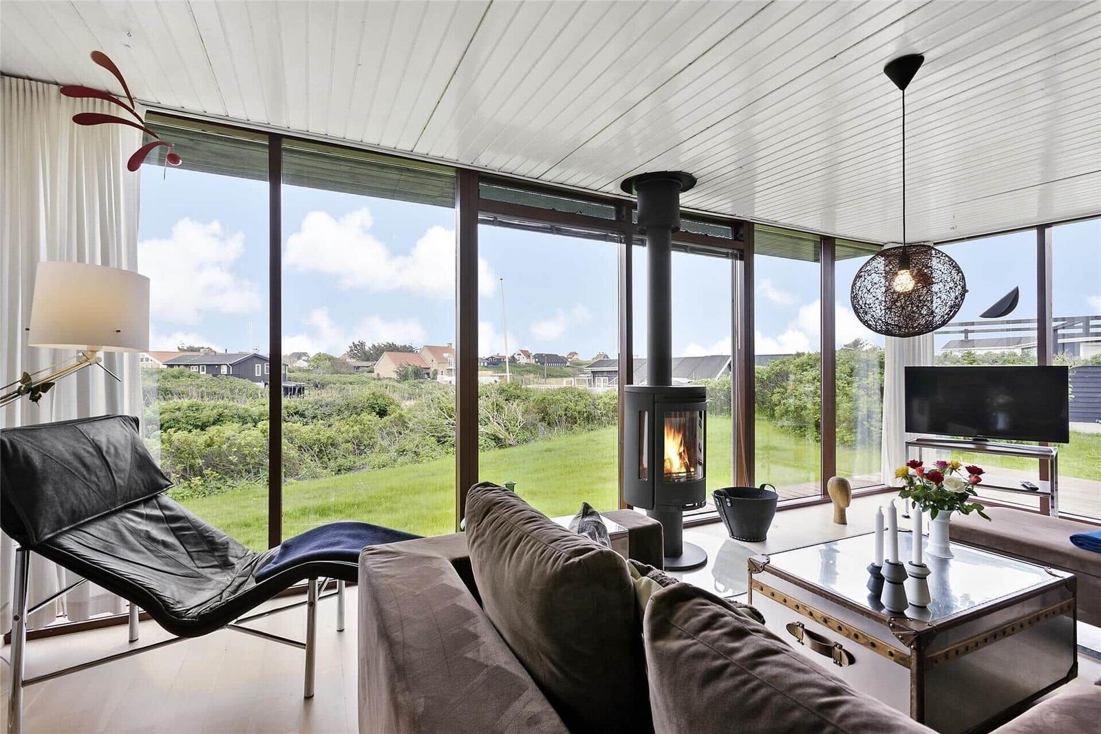 Wohnzimmer mit Kamin, großem Fenster und moderner Einrichtung.