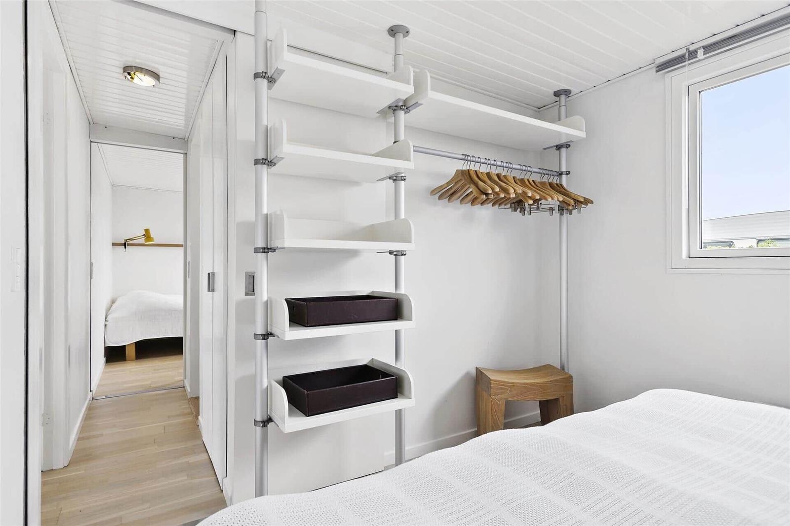Schlafzimmer mit Kleiderschrank, Fenster und Betten im Hintergrund.