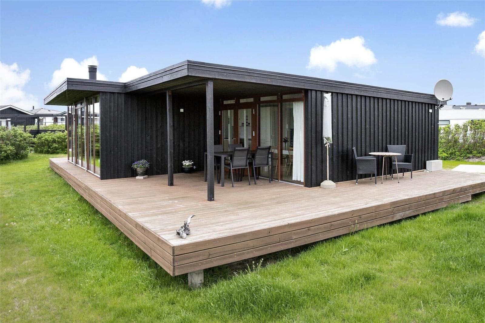Moderne Holzhütte mit großem Balkon und Sitzgelegenheiten im Freien.