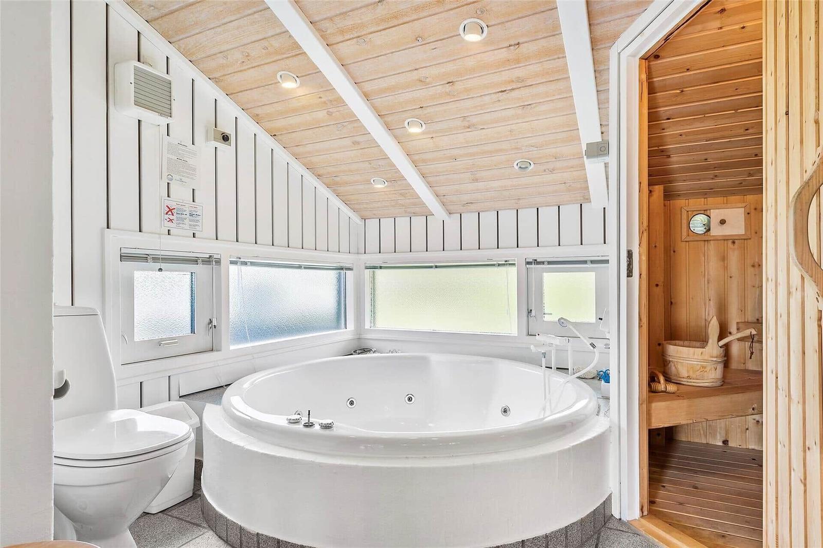 Bad mit Whirlpool, Toilette und angrenzender Sauna.