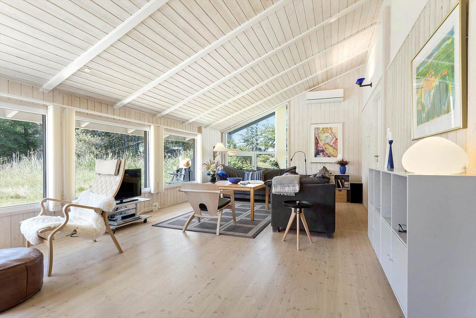 Wohnzimmer mit Holzboden, großen Fenstern und moderner Einrichtung.