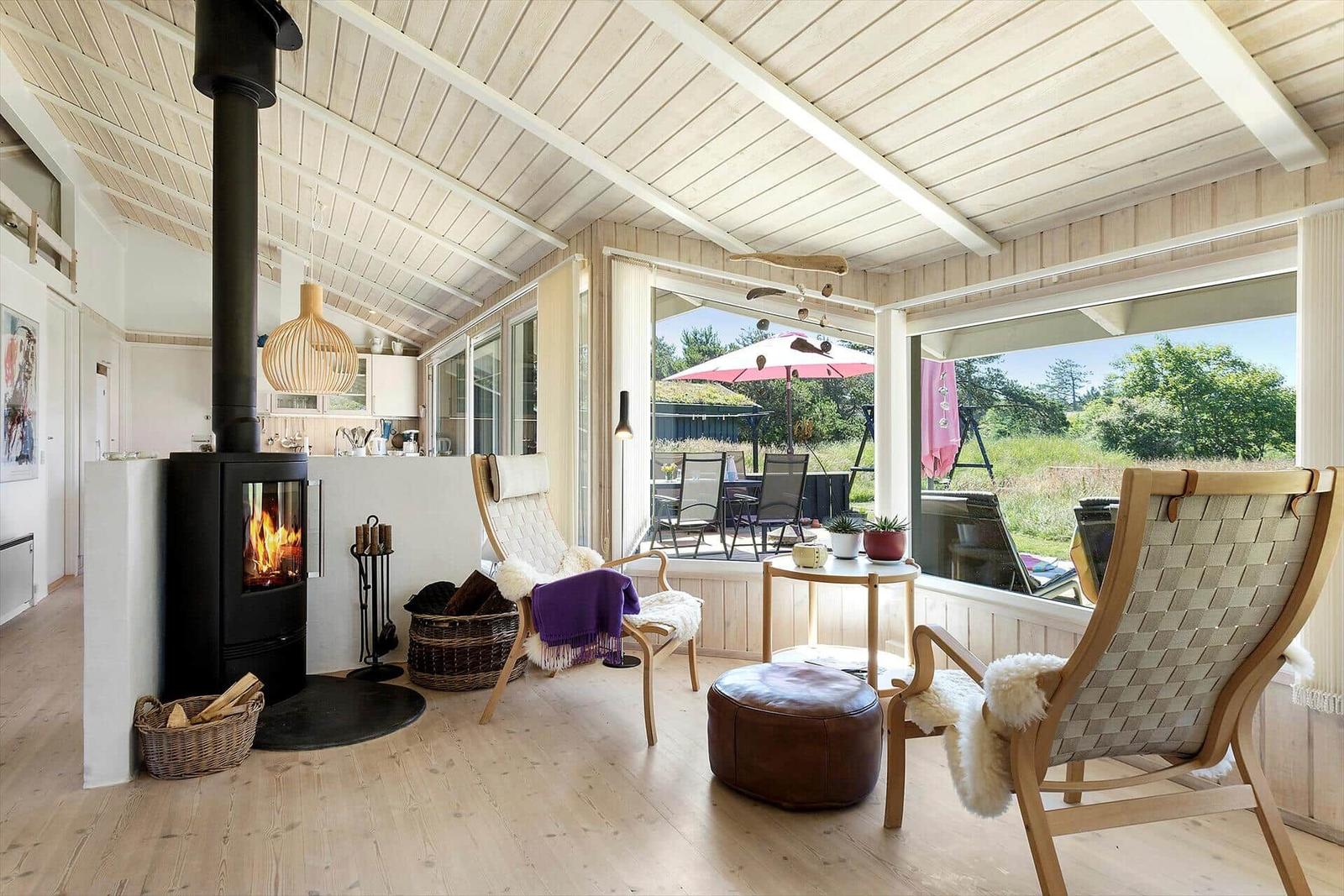 Wohnbereich mit Kamin, Sesseln und Blick auf Terrasse