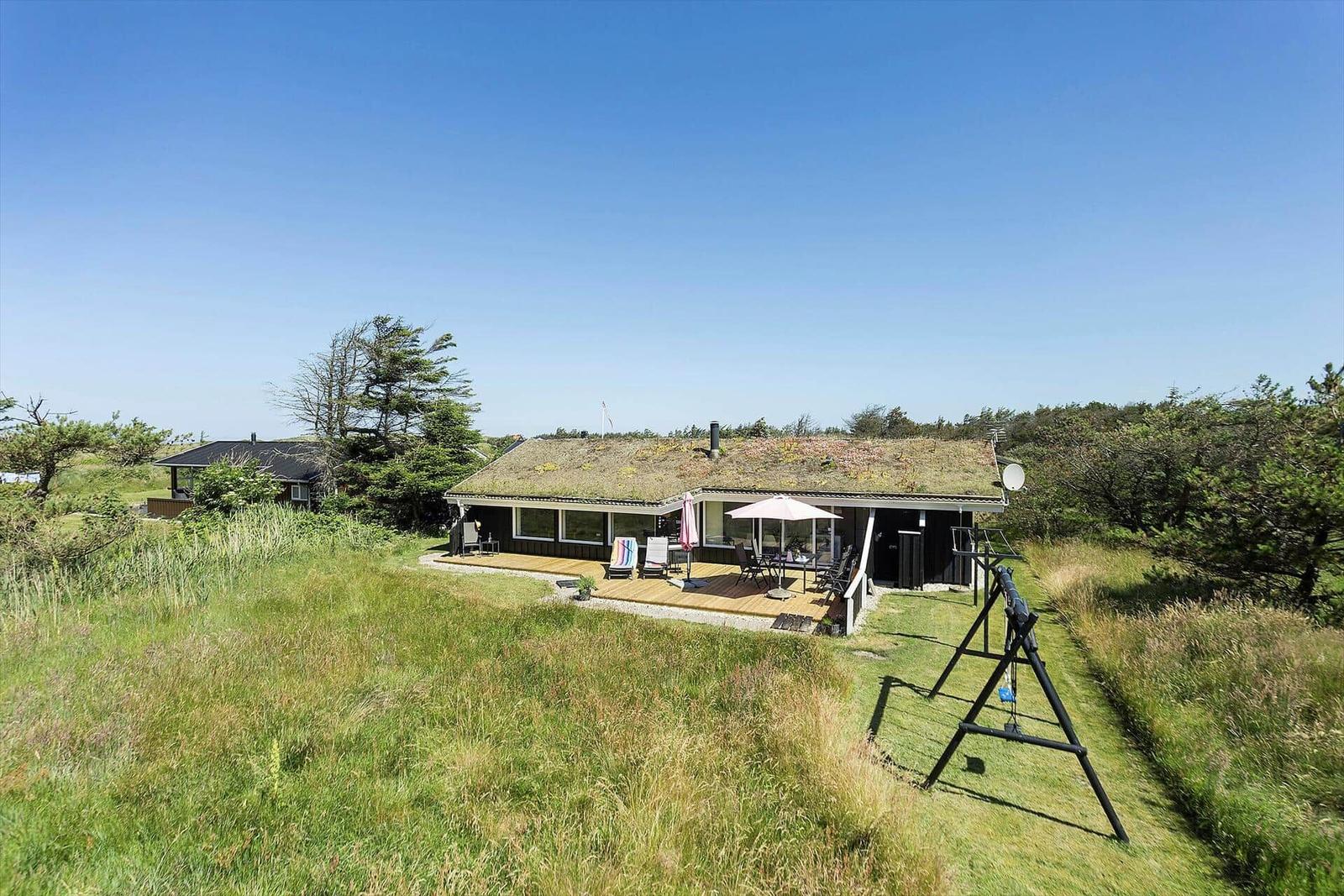 Haus mit grünem Dach und Terrasse im Grasland.