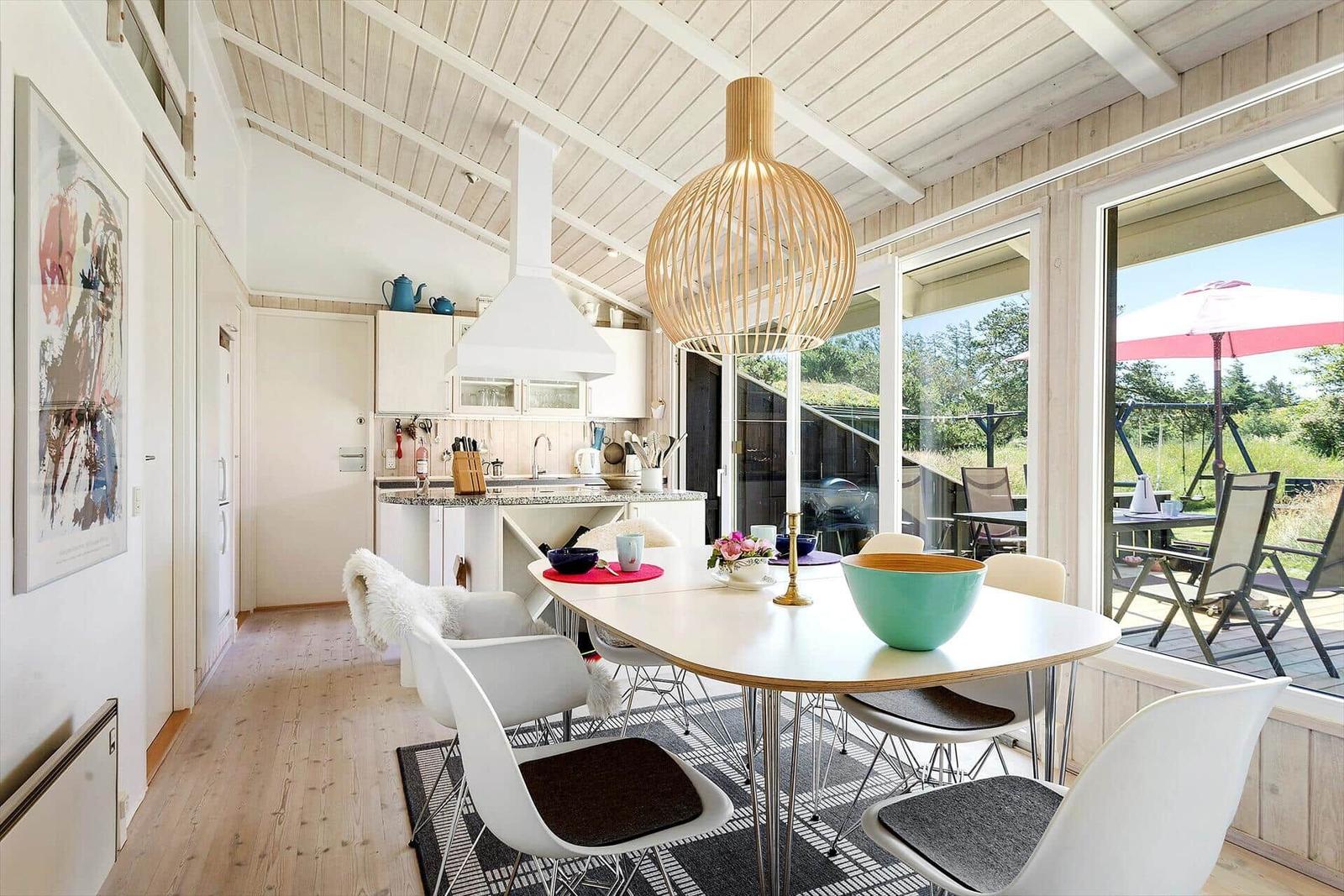 Essbereich mit Tisch und Stühlen, Küche und Terrasse mit Gartenblick.