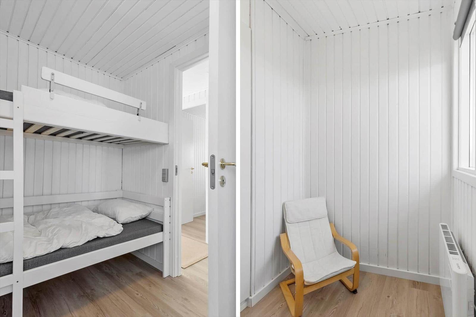 Zimmer mit Doppelstockbett und Sitzgelegenheit. Weiße Wände und Holzboden.