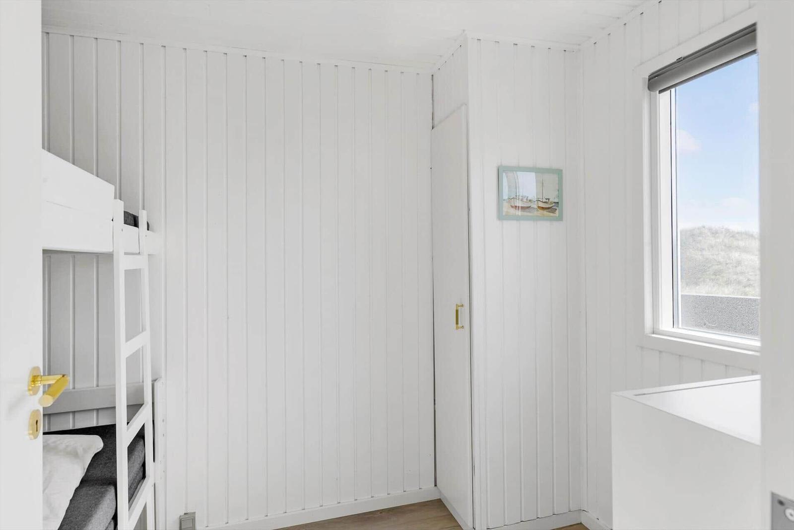 Schlafzimmer mit Doppelstockbett, Fenster und Wandbild.