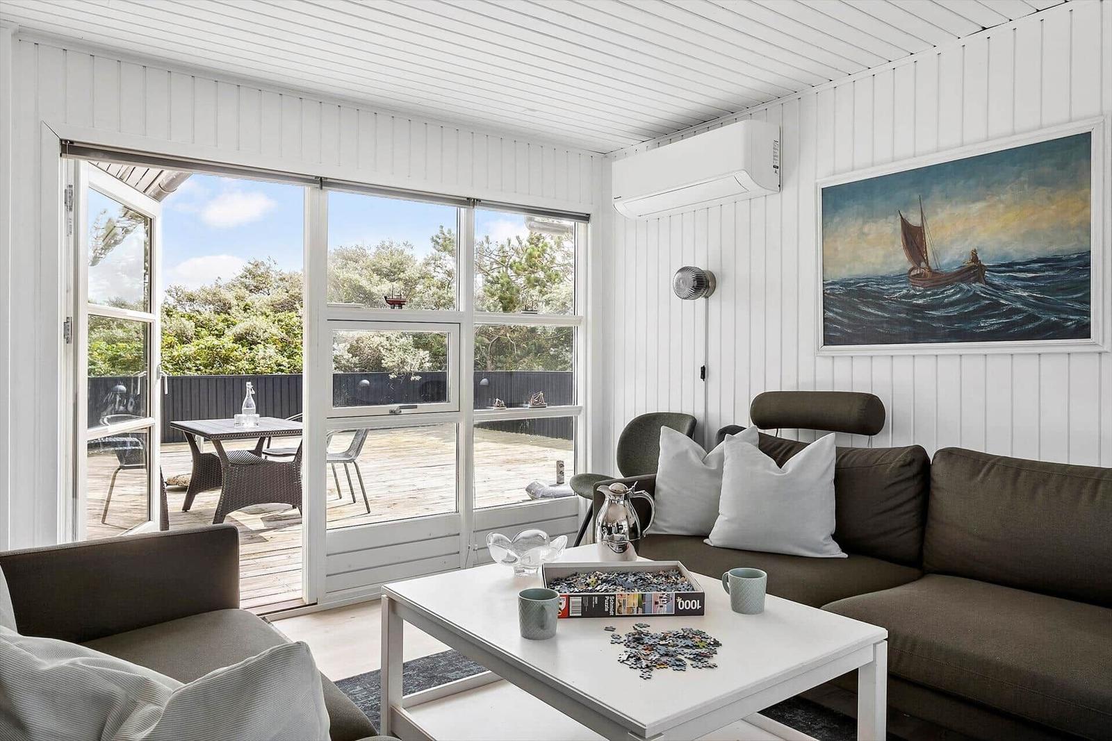 Wohnzimmer mit Sofa, Tisch und Blick auf Terrasse