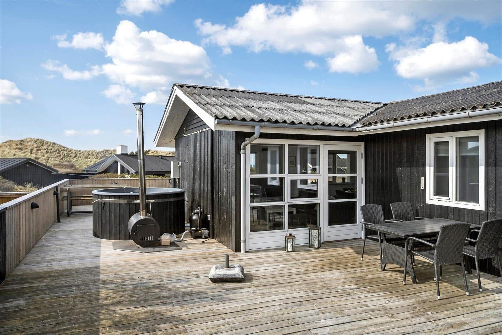 Terrasse mit Hot Tub, Sitzgruppe und Blick auf Dünen.