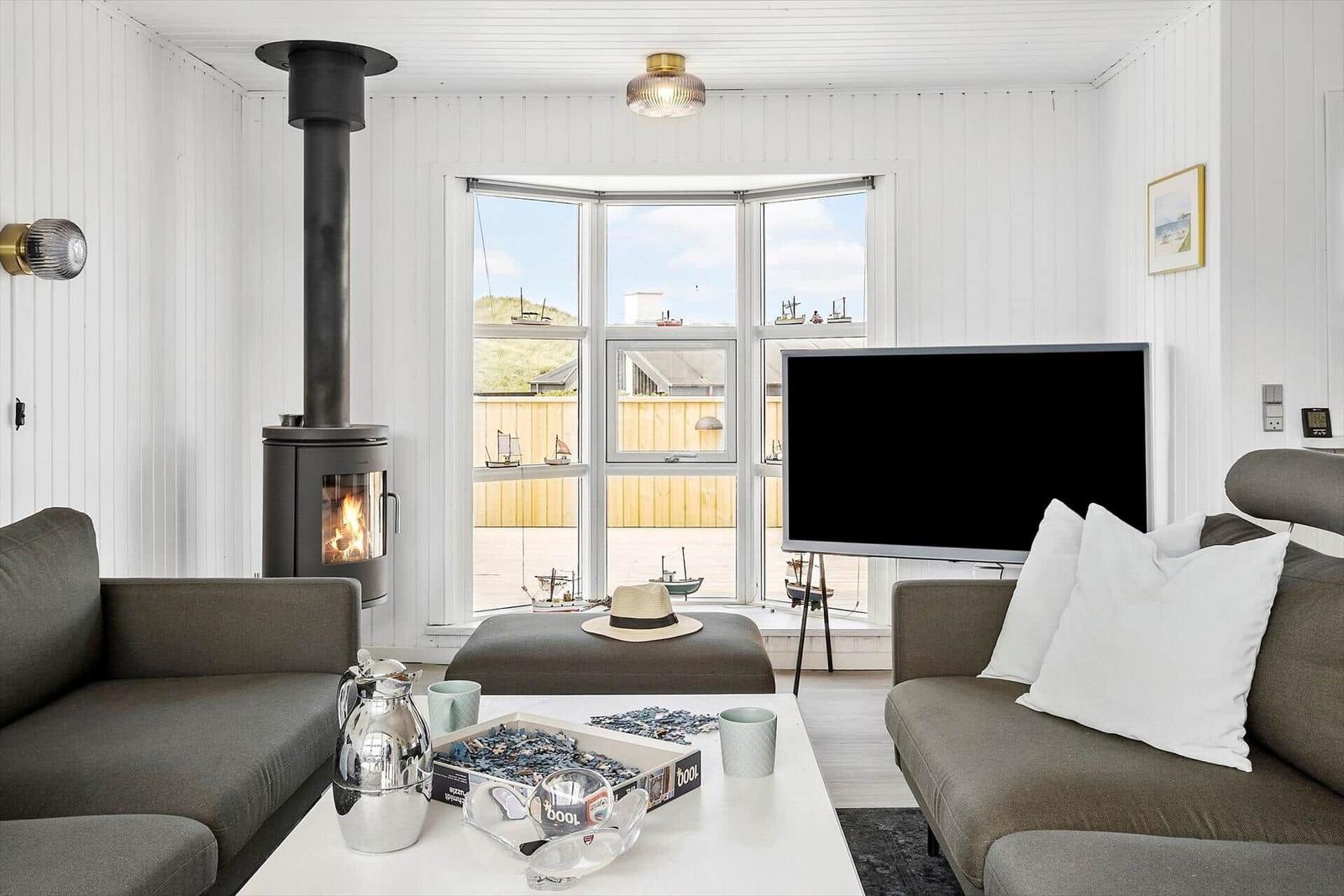 Wohnzimmer mit Kamin, Sofa, Fernseher und Blick auf den Hafen.
