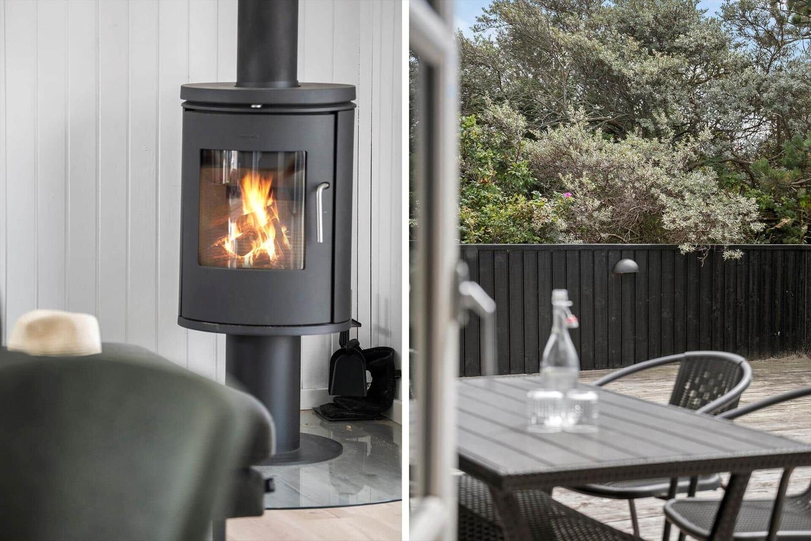Innen: Holzofen mit brennendem Feuer. Außen: Terrasse mit Tisch, Stühlen und Blick auf Grünflächen.