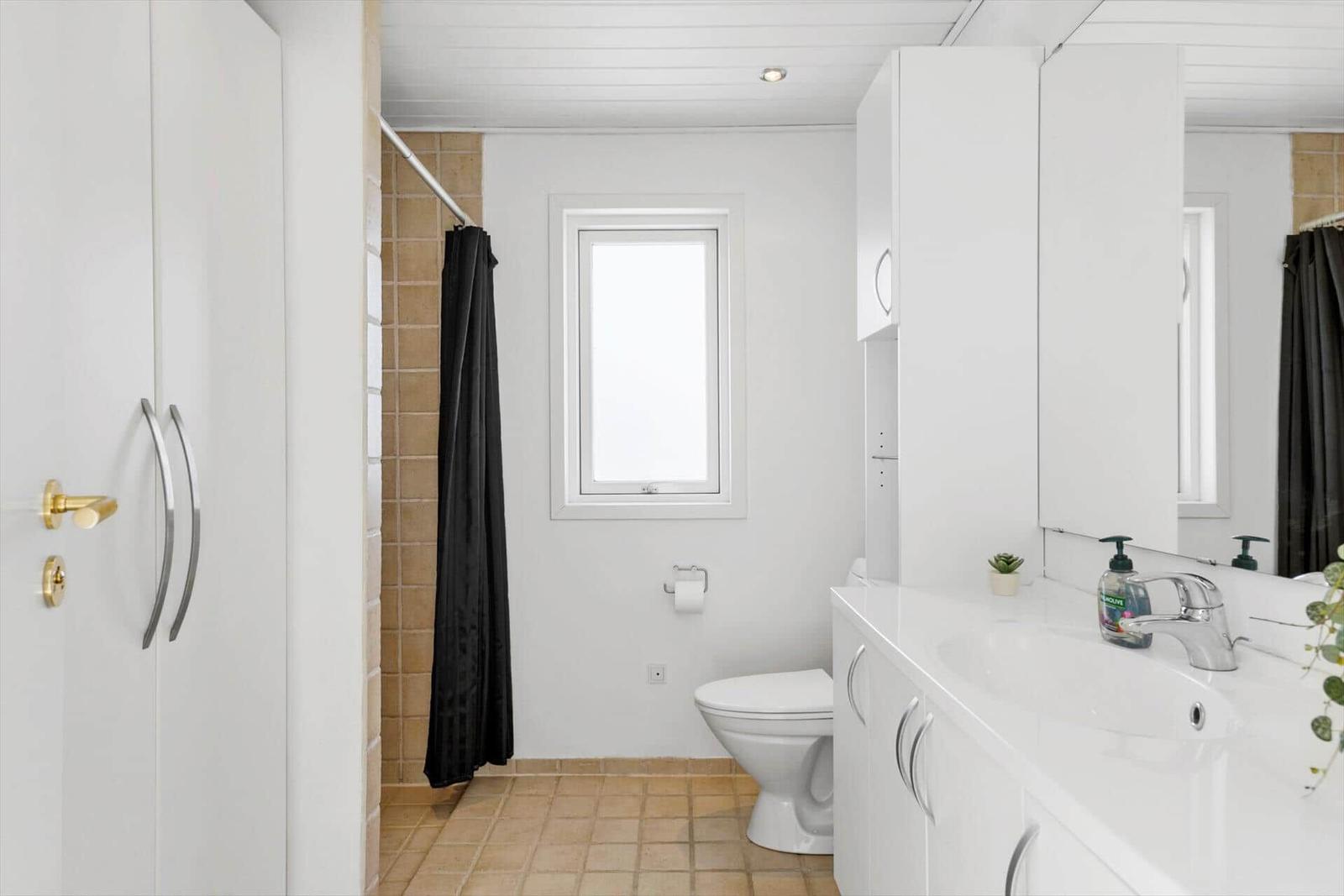 Badezimmer mit Dusche, Toilette und Waschbecken mit Spiegel