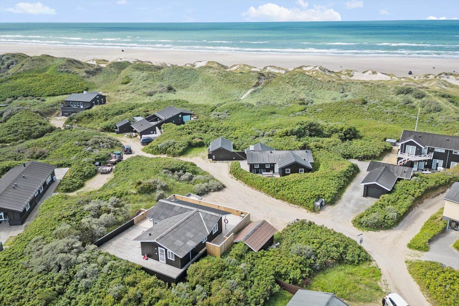Meerfront-Villa mit Garten und Strandblick. Mehrere Häuser in Dünenlandschaft.