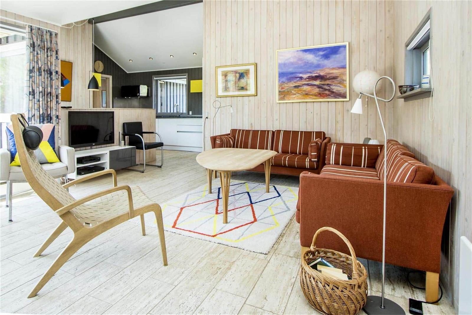 Wohnzimmer mit Sofa, Tisch und Fernseher. Holzwand und helles Parkett.